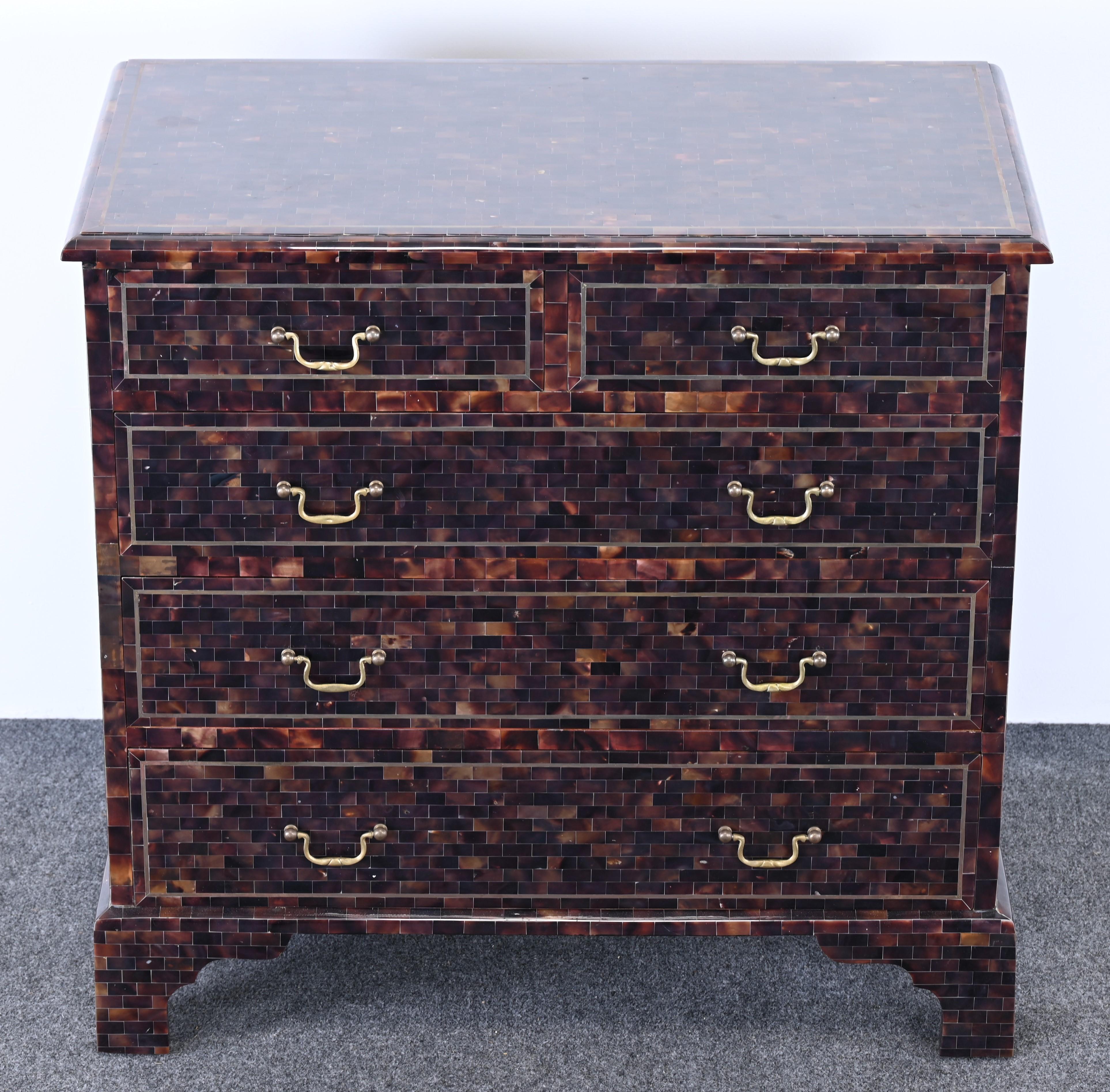 A handsome tessellated horn chest of drawers by Maitland Smith. This beautiful chest has bracket feet and George III brass hardware. There are two small drawers over three larger drawers for ample storage. The chest has brass inlay around all of the