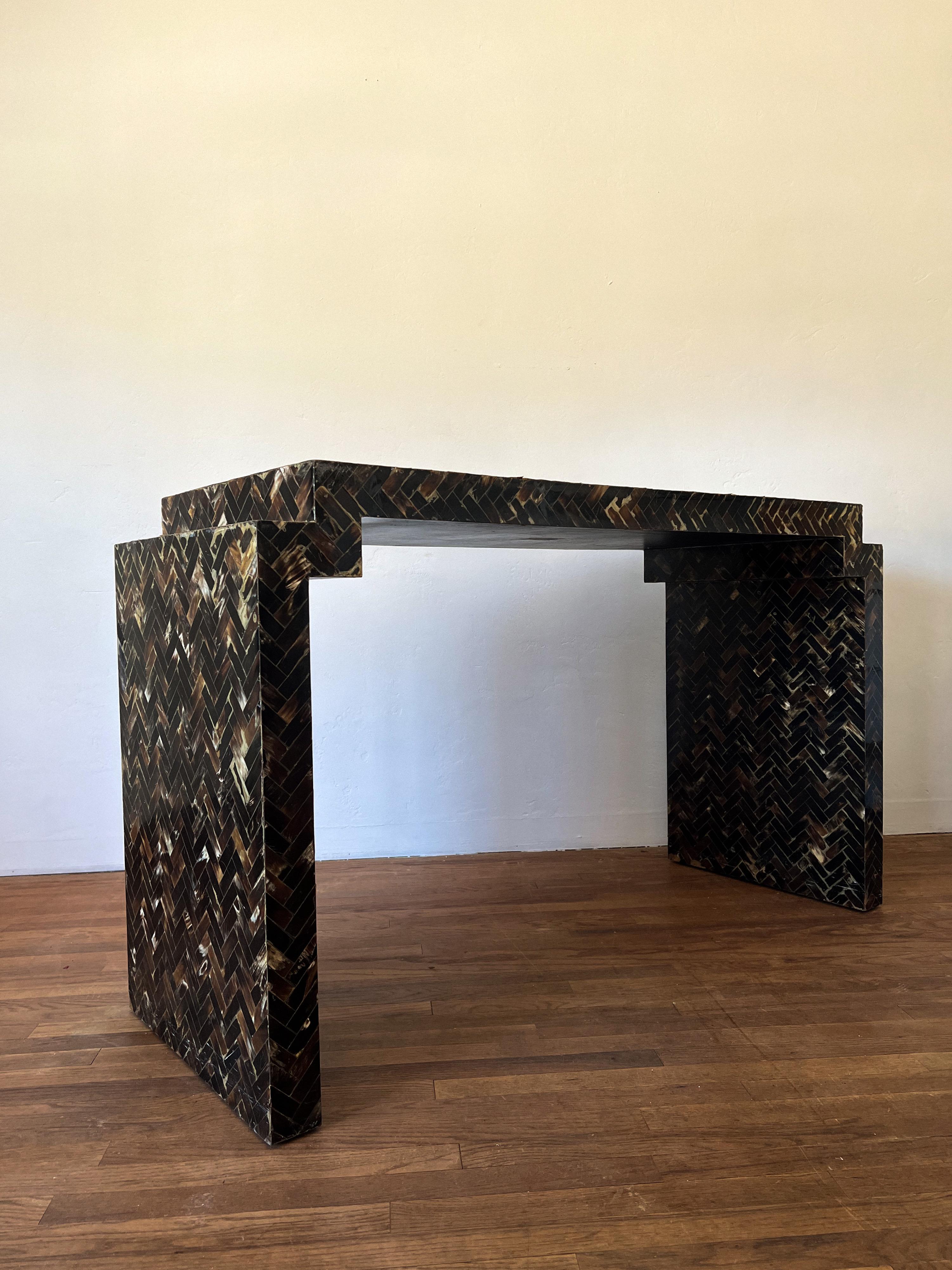 Mid-Century Modern console table with geometric step edges covered in tessellated horn and attributed to Enrique Garcel. Marked “Made in Colombia”.