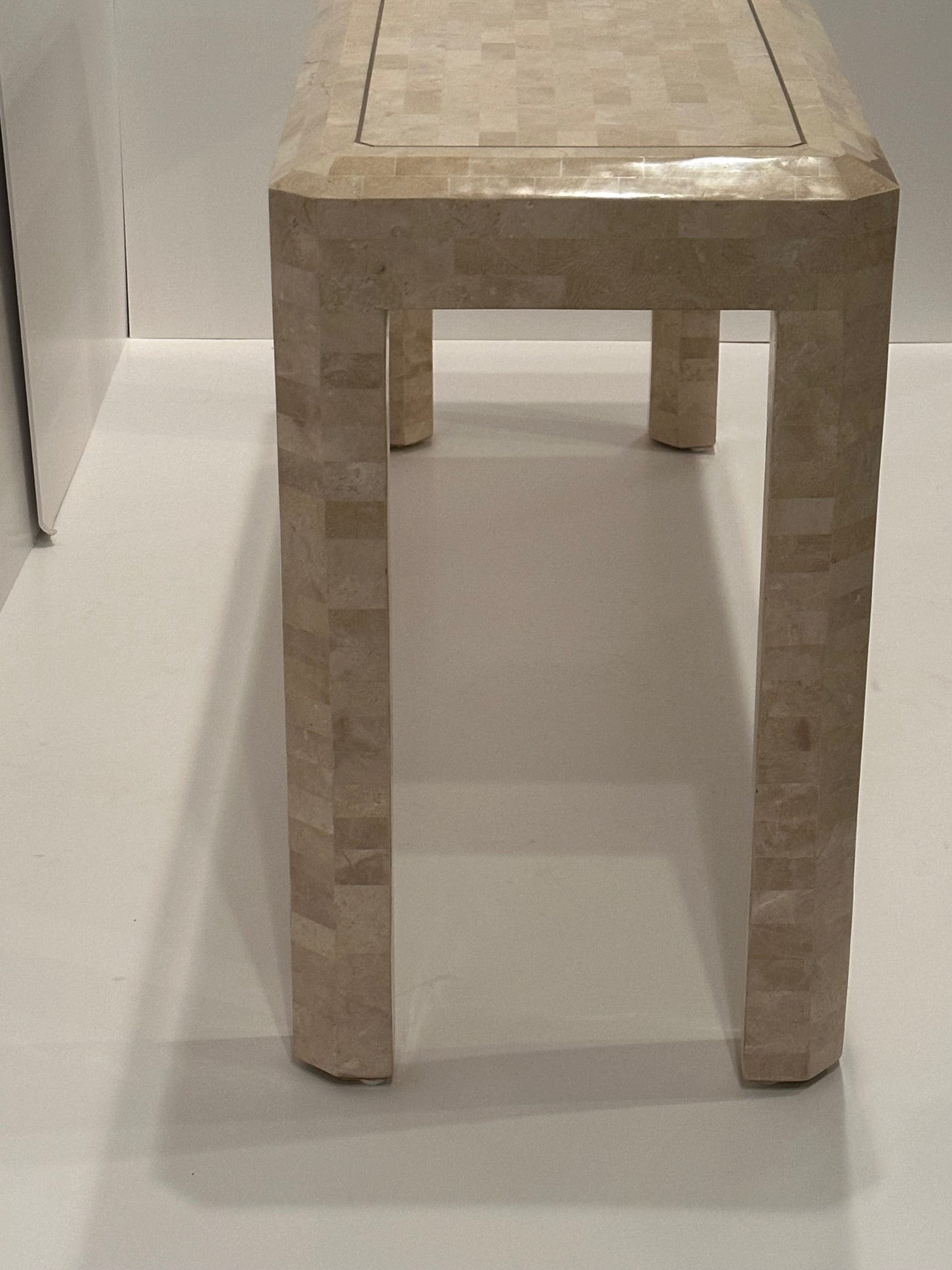 Glamorous creamy tessellated stone console table having brass inlay decoration.  Simple streamlined silhouette makes this piece mix well in any decor.
