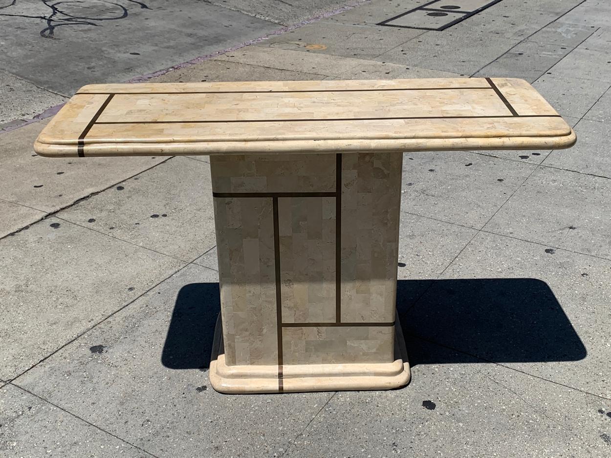 Beutiful console table executed in tessellated stone and brass inlay.

The piece has a beautiful geometric brass design on the base and top.

The brass has a beautiful aged patina and the stone a rosy, pinkish color.

Measurements:
48 inches
