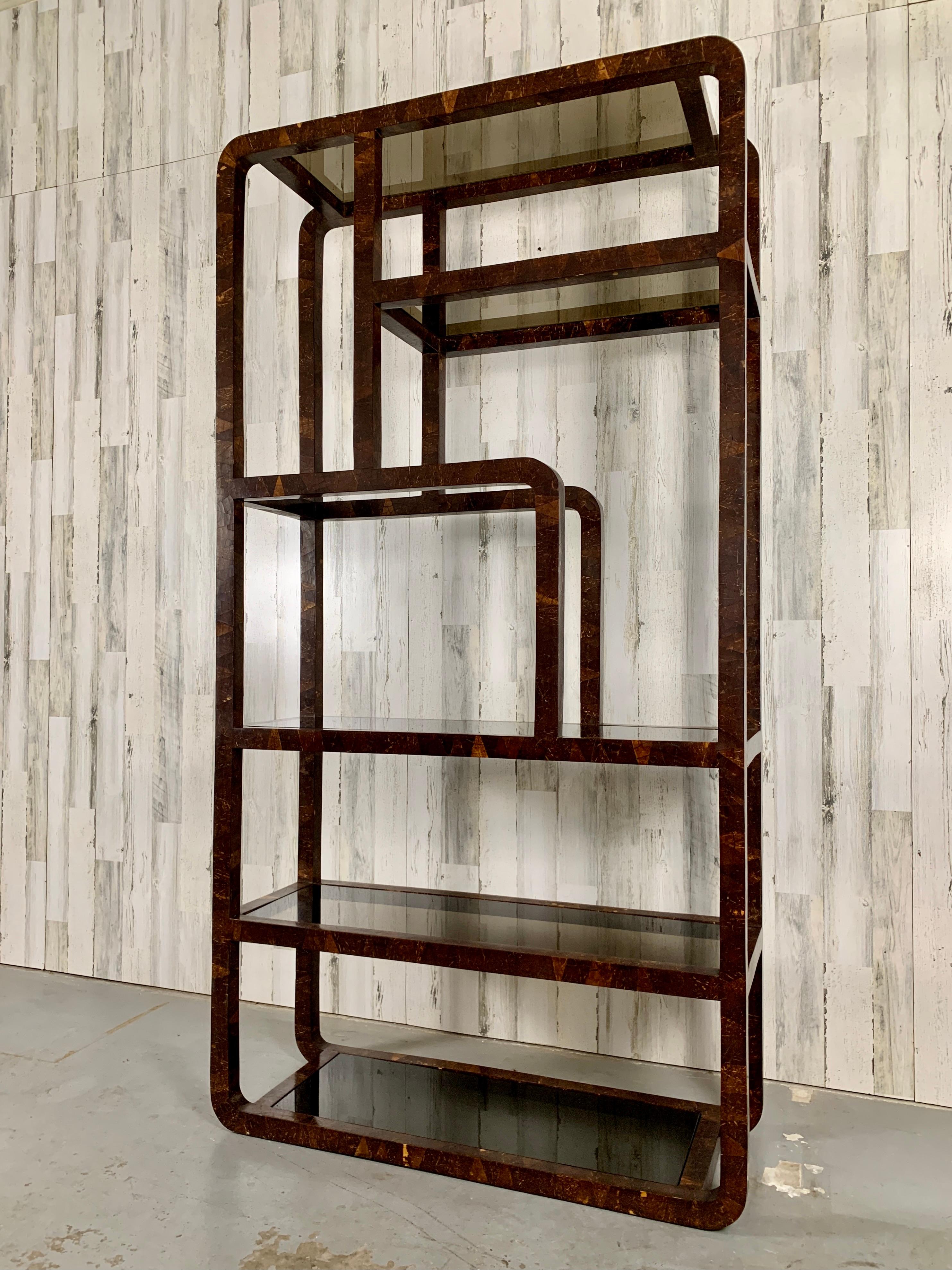 1980's modern freestanding unit wrapped in coconut shell veneer in a geometric pattern with smoked glass shelves.
Decorative on all sides so it can be used as a room divider.