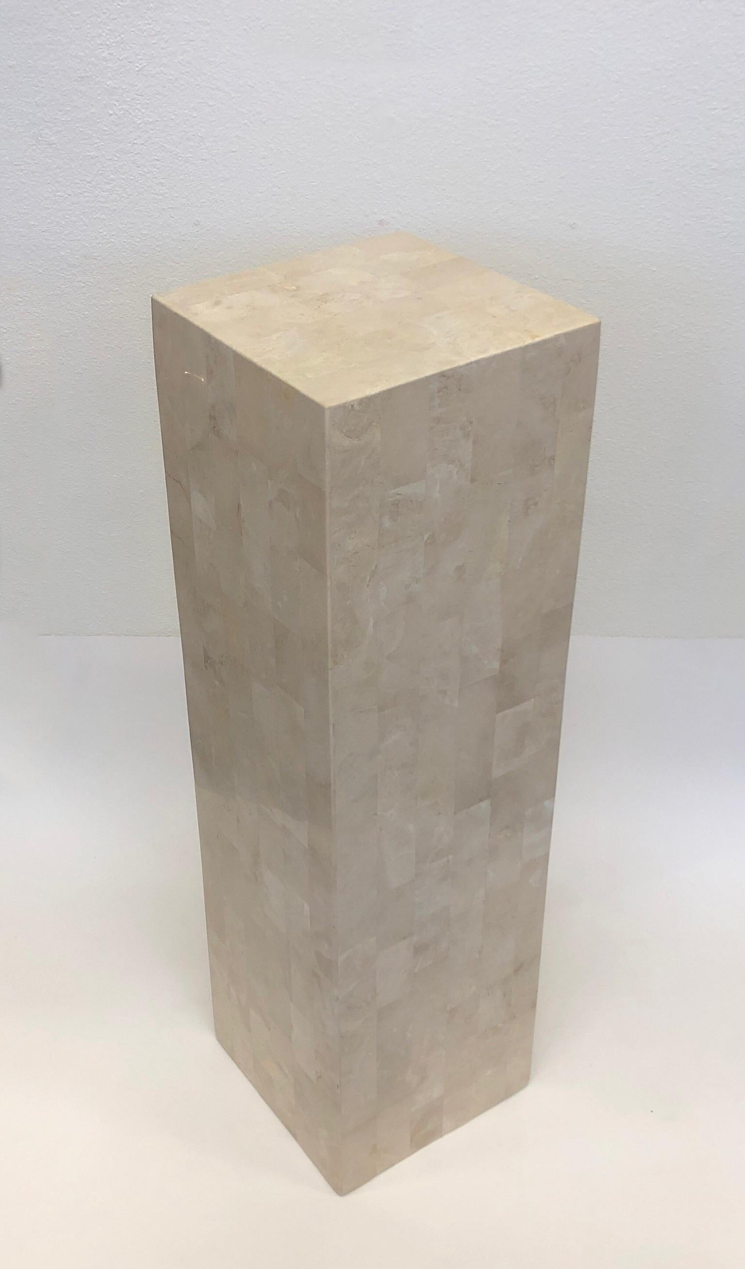 A simple and elegant 1980s tessellated stone pedestal by Marquis Collection of Beverly Hills. The pedestal has been newly professionally cleaned. The pedestal is constructed of wood with tessellated stone over it. 
Dimensions: 42.25” high 12” wide