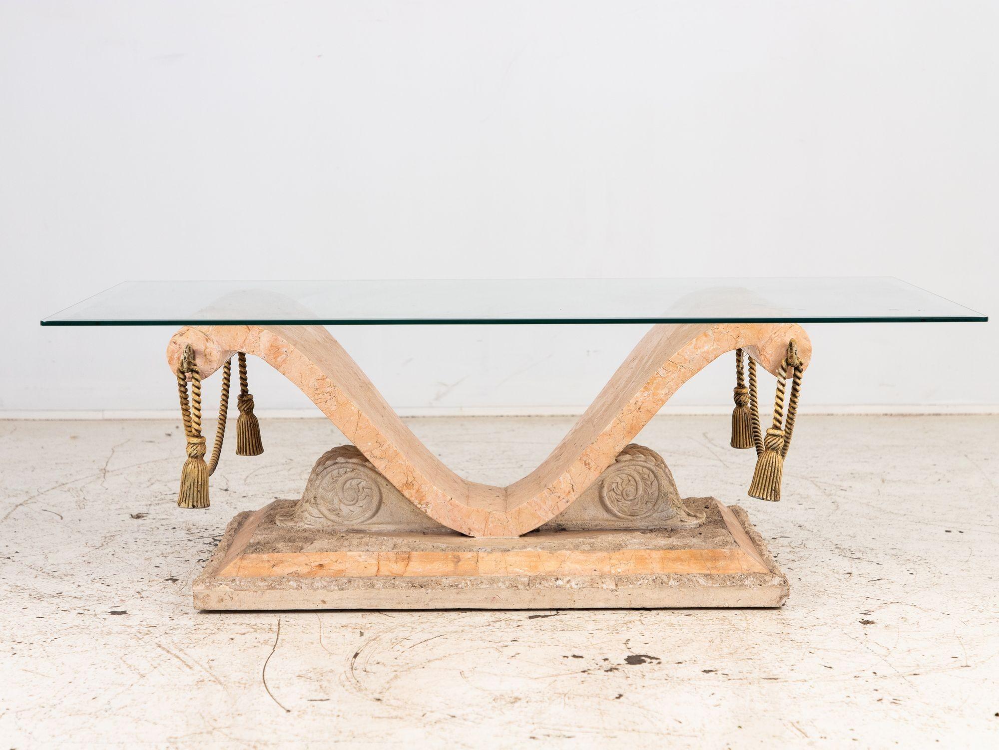 This stunning rectangular cocktail table features a glass top resting on a meticulously crafted tessellated travertine base, exuding sophistication and architectural flair. Acanthus leaf supports add a touch of classical elegance, while metal rope