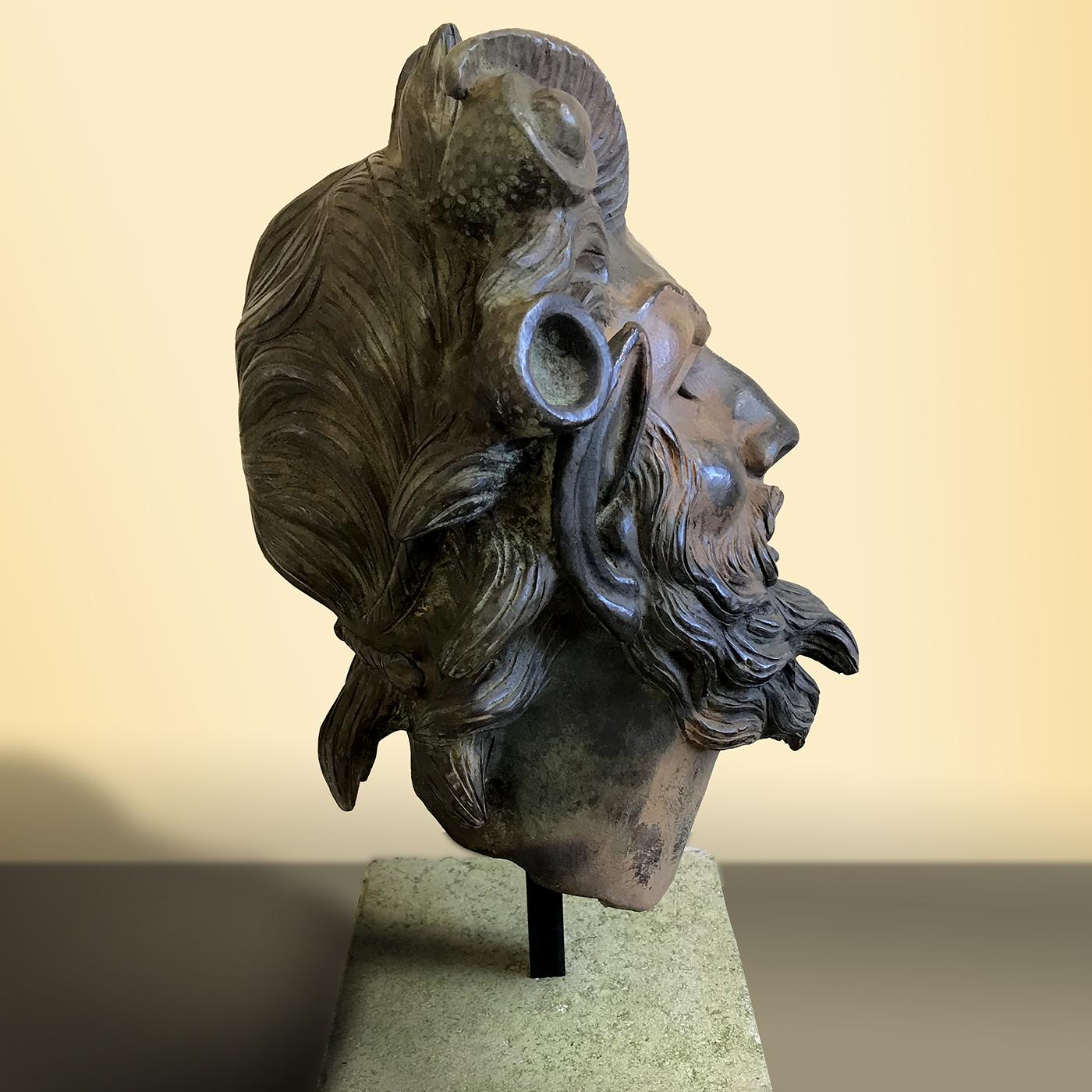 Dieses exquisite Stück stellt den Kopf eines bärtigen Fauns dar, der mit seinen Ziegenhörnern und länglichen Ohren deutlich zu erkennen ist. Der Faun war das römische Äquivalent des altgriechischen Satyrs, ein mythologisches Wesen, das halb Mensch,