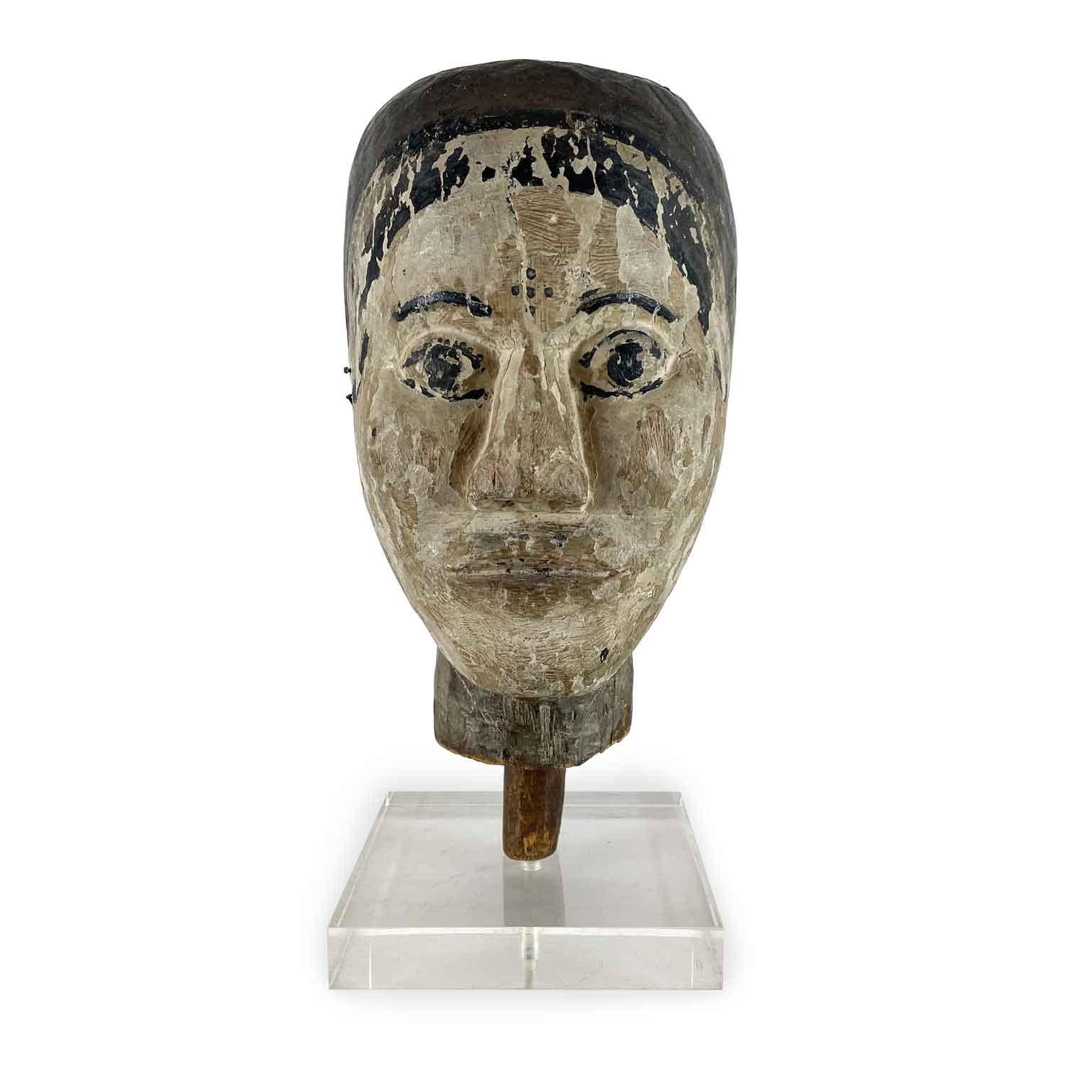 Testa Laccata In Legno Scolpito Primi 1900 montata su di una base in plexiglass alta 3 cm. con il collo troncato per l’innesto al corpo per il tramite di una spina. Pur avendo delle cadute di colore diffuse nella laccatura il volto di questa antica