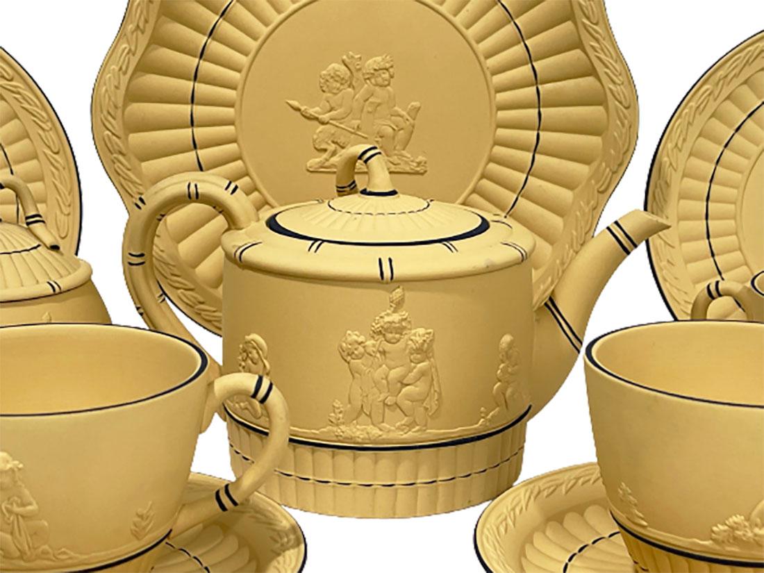 Tête-à-tête tea service by Wedgwood
A Black on yellow cane Jasperware wedgwood stoneware with black lines and scene of Putti
A serving tea set with a serving plate, 2 plates, a tea pot, 2 cups and saucers, milk jug and a sugar bowl, and 2 lidded