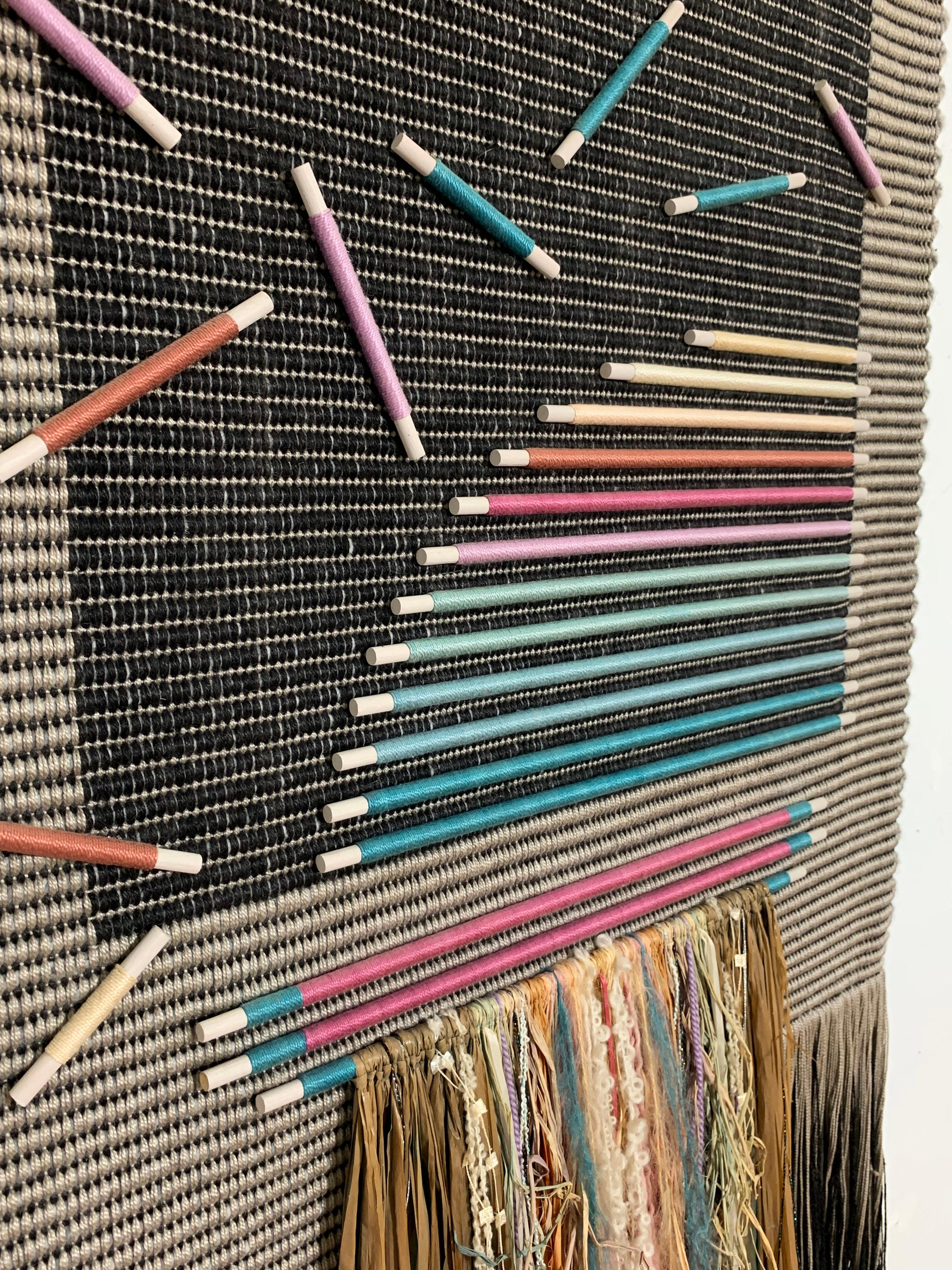 Skillfully made post-modern circa 1980s textile art weaving of twisted cotton matting applied with a scattering of wooden dowels wound in colorful silk threads. A double row of raffia ribbon and mixed fiber fringe work creates a cascading effect