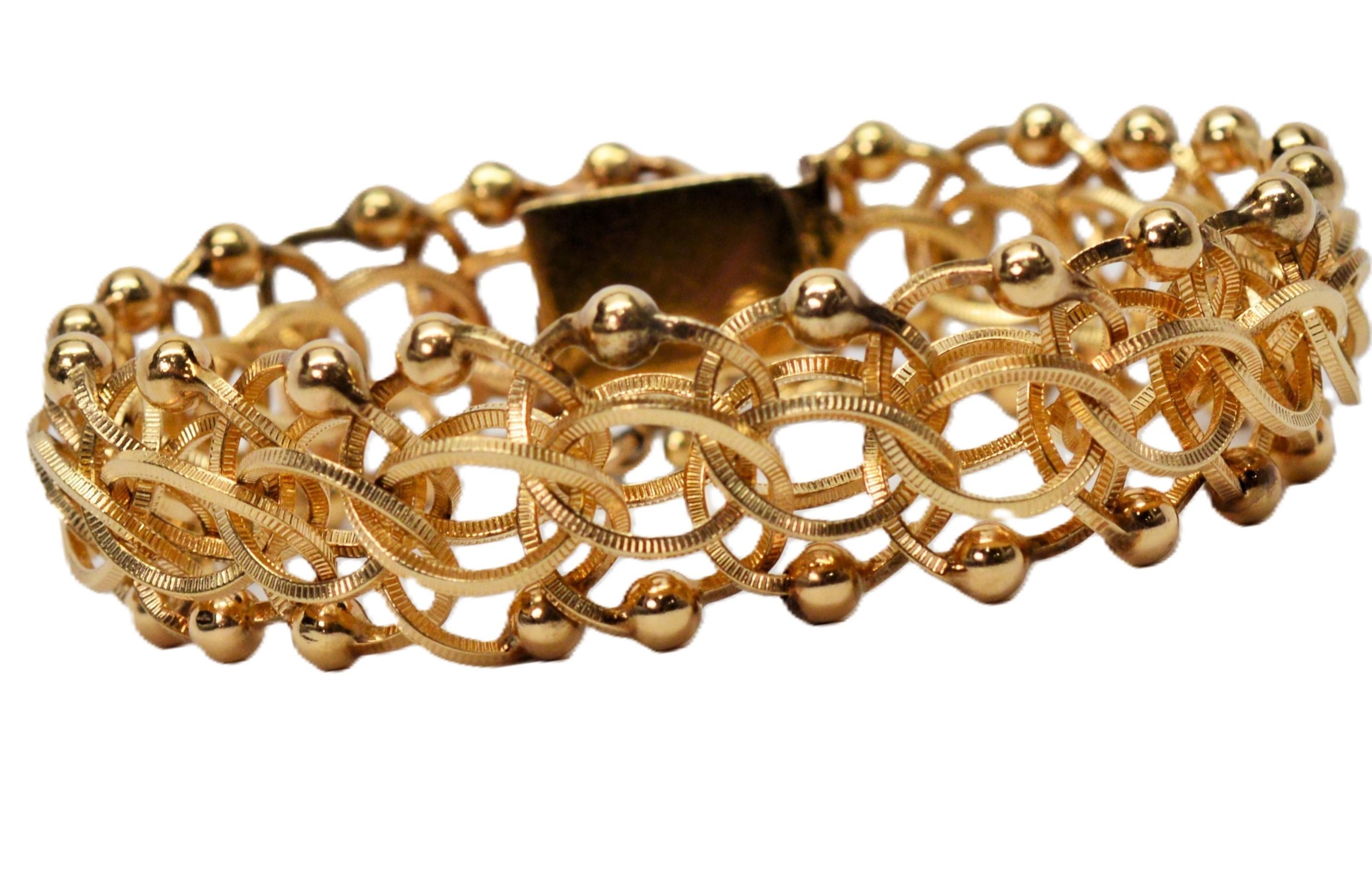 Questo bracciale degli anni '50 è caratterizzato da un'attenzione particolare per i dettagli, con l'uso di una texture sulle maglie multiple intrecciate in oro giallo a 14 carati che creano un motivo a catena molto attraente.  A sottolineare