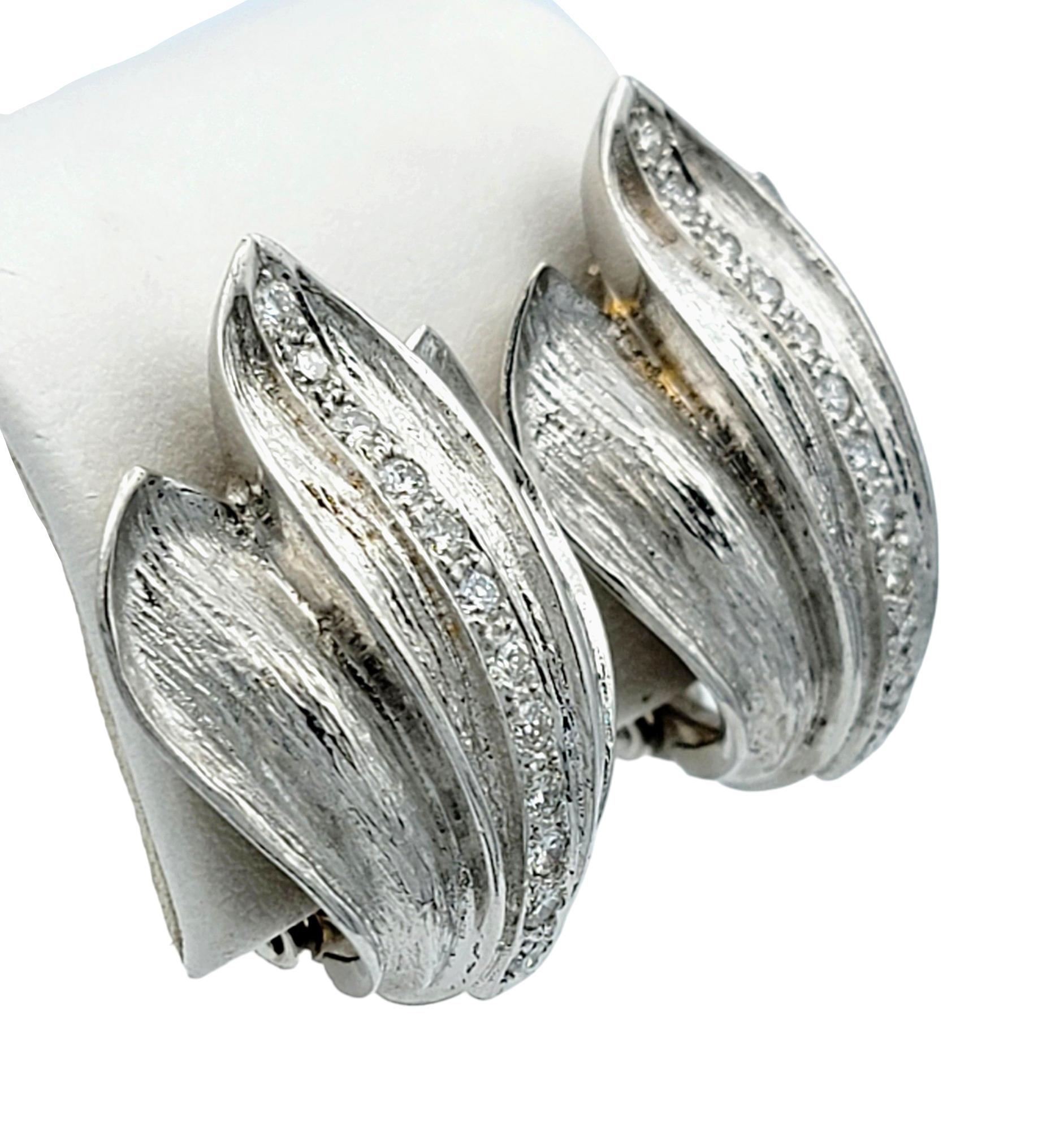 This exquisite pair of flame motif clip-on earrings are artfully crafted in 18 karat white gold. These elegant earrings feature a finely textured design adorned at the center with sparkling round diamonds that enhance the beauty and sophisticated