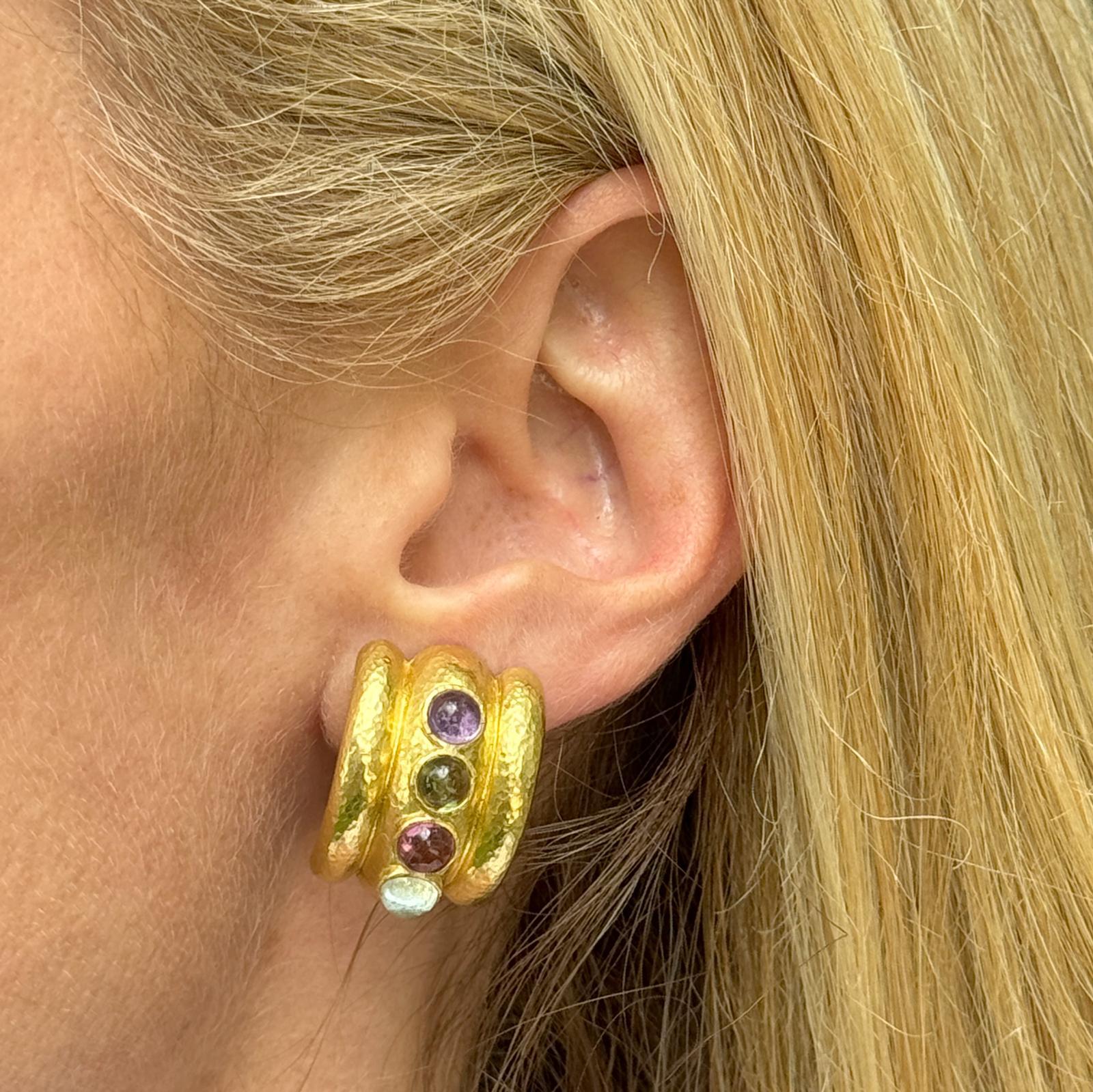 The Textured 18 Karat Yellow Gold Earrings gemstone earrings are a vibrant and elegant accessory. These half hoop style earrings feature a luxurious textured gold finish, showcasing bezel-set amethyst, tourmaline, peridot, and topaz gemstones. The
