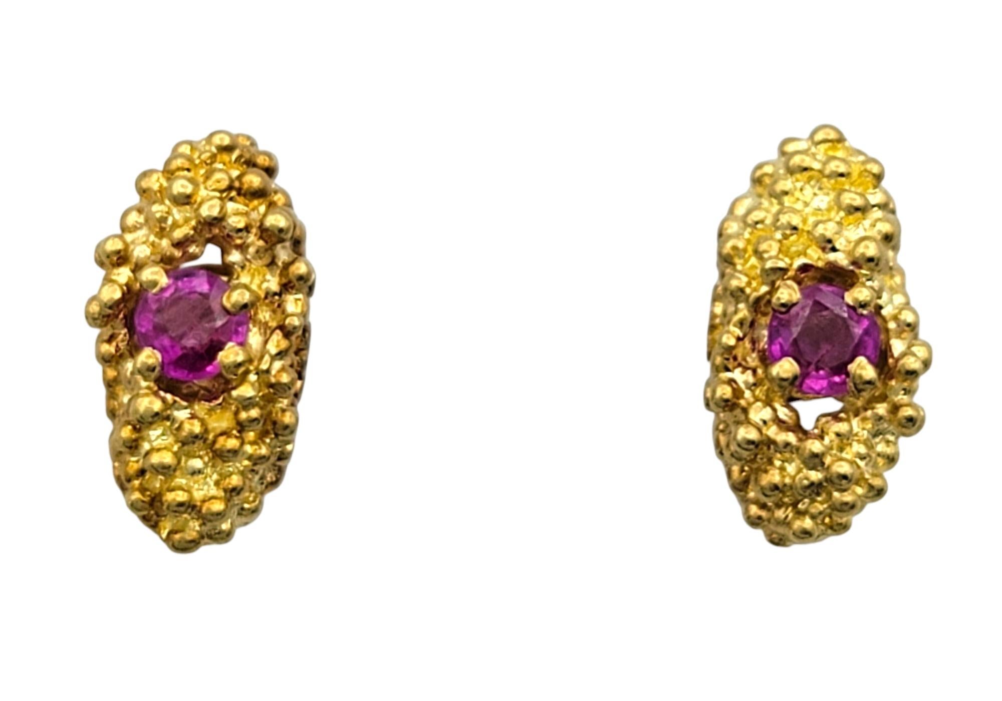 Questi orecchini ispirati alla natura presentano un design ricco di texture in oro giallo 18 carati, formando una forma organica allungata che culla un vibrante rubino al centro di ogni perno. La superficie d'oro testurizzata aggiunge profondità e