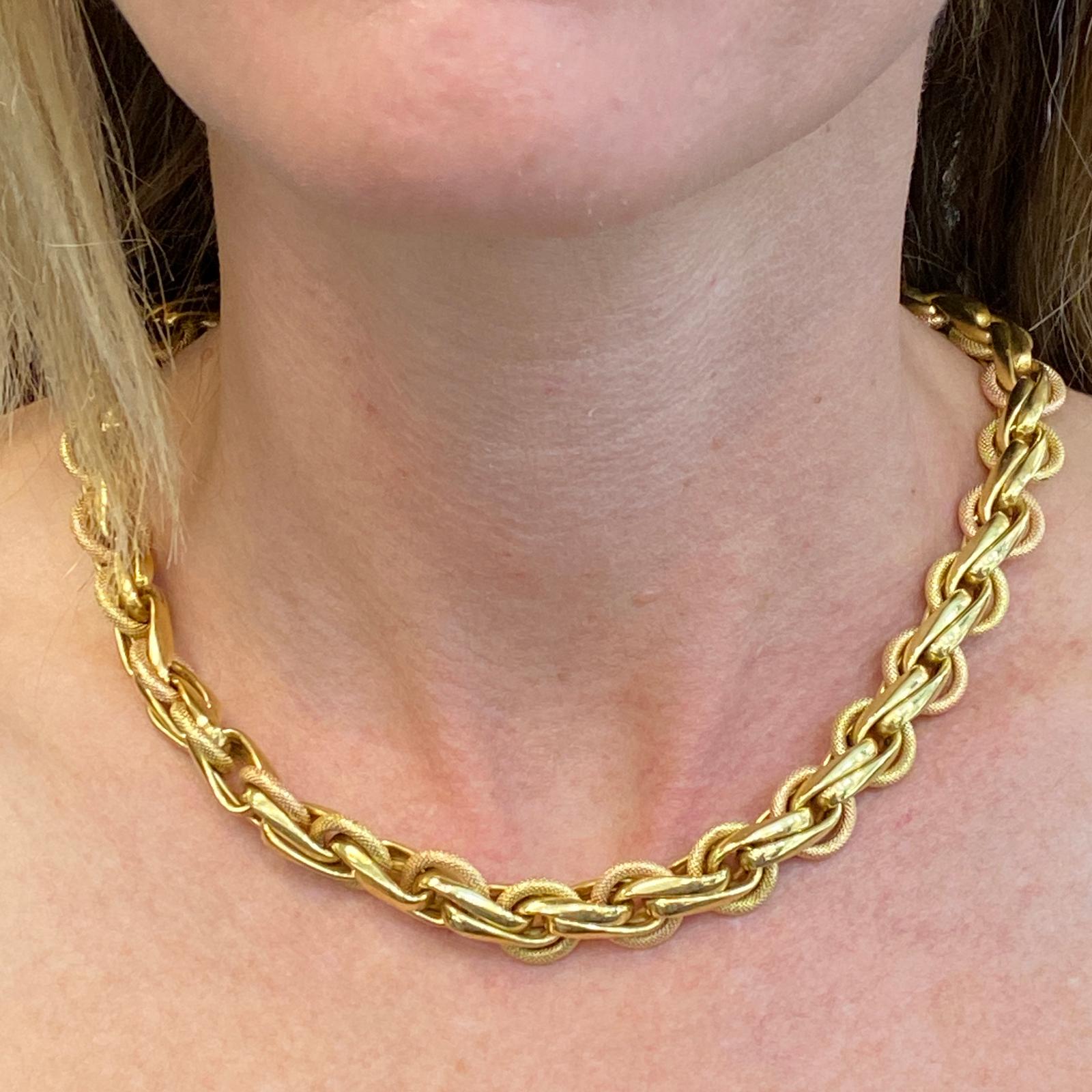 Textured vintage link necklace fashioned in 18 karat yellow and rose gold. The link necklace features high polish yellow gold and textured rose gold links with a cabochon lapis lazuli gemstone clasp. The necklace measures 17 inches in length and