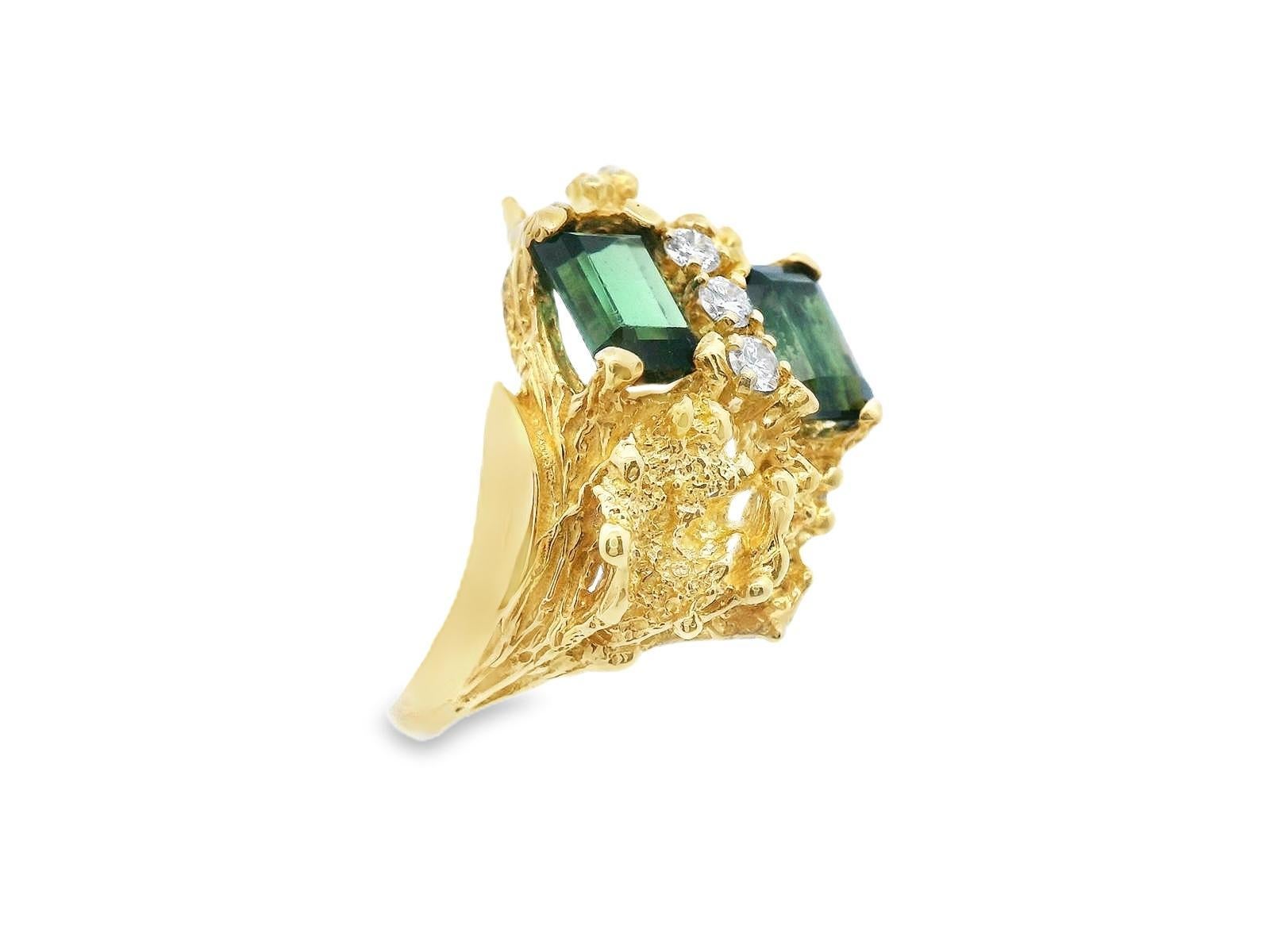 This textured 18k yellow gold ring features stunning natural green tourmaline and diamond. There are 1.8 carats total weight of emerald cut tourmaline that showcases a vivid green hue. Resting between the tourmaline are 3 round cut, G/H color, VS