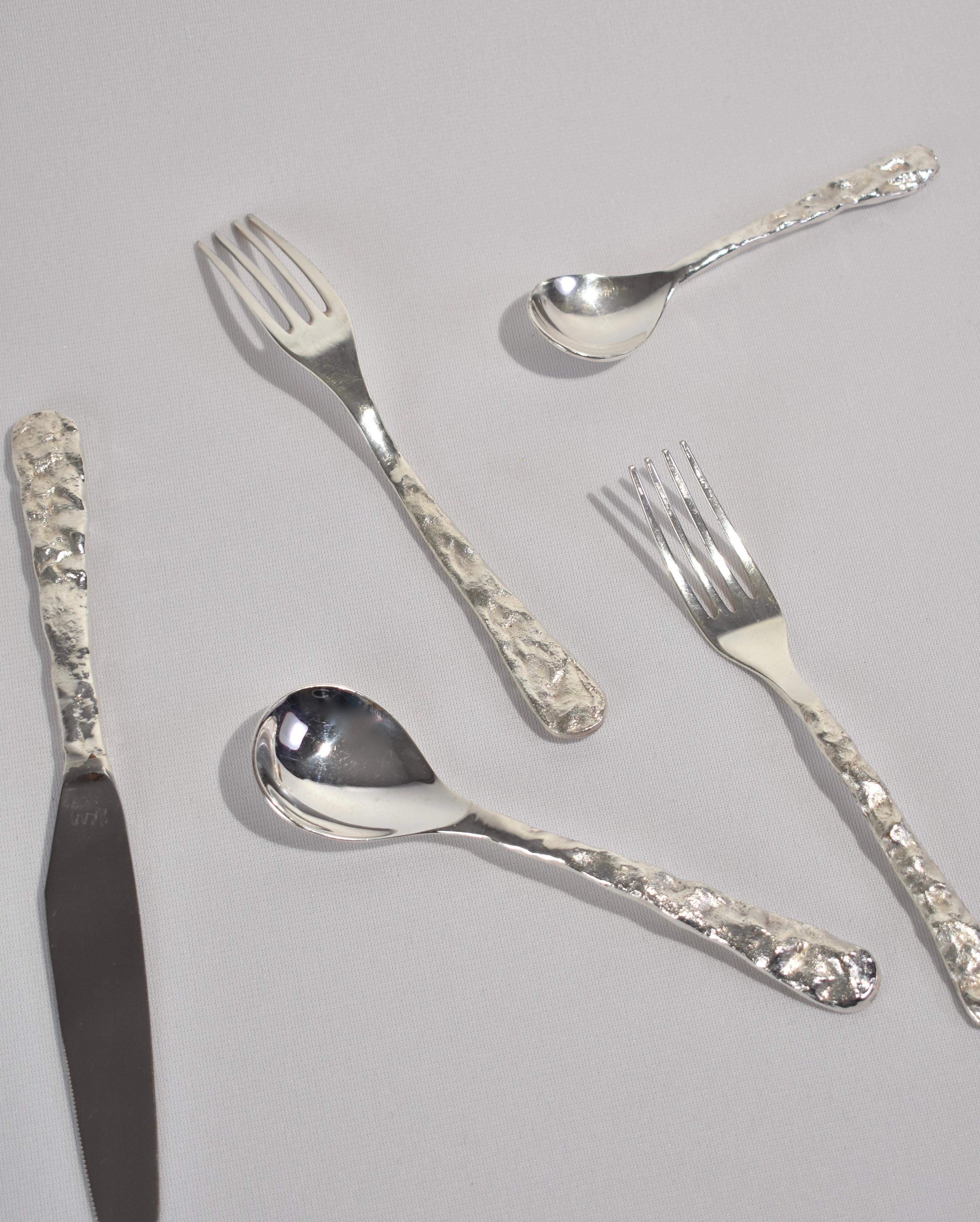 Vintage textured stainless steel flatware set of five pieces (one knife, two spoons, two forks) by Michael Aram. Each knife is signed Aram '92.