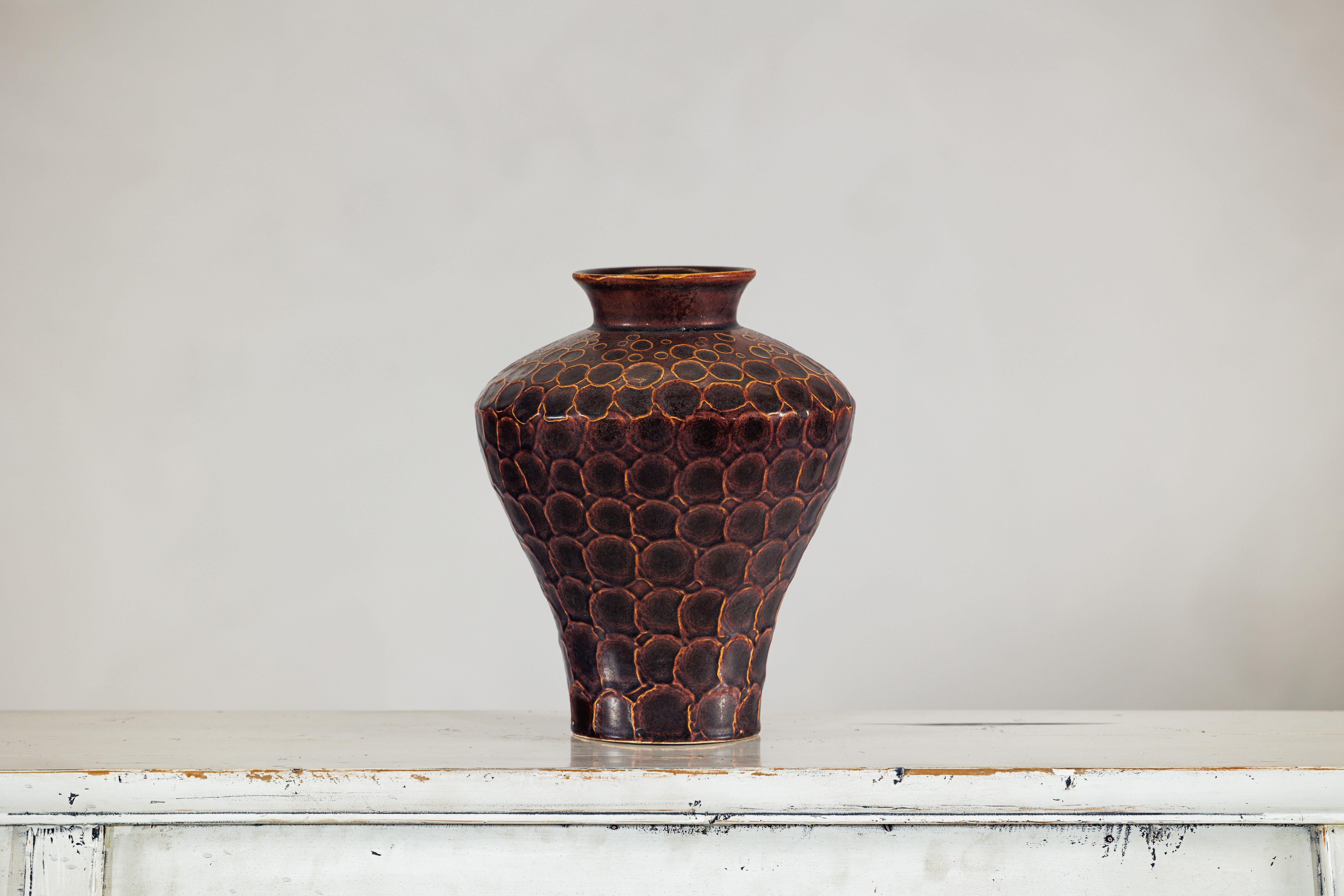 Audace, tattile e inconfondibilmente artigianale, questo vaso in ceramica si fa notare appena entri nella stanza. Questo vaso in ceramica riccamente strutturato offre una presenza sorprendente, definita dallo smalto marrone intenso e dal