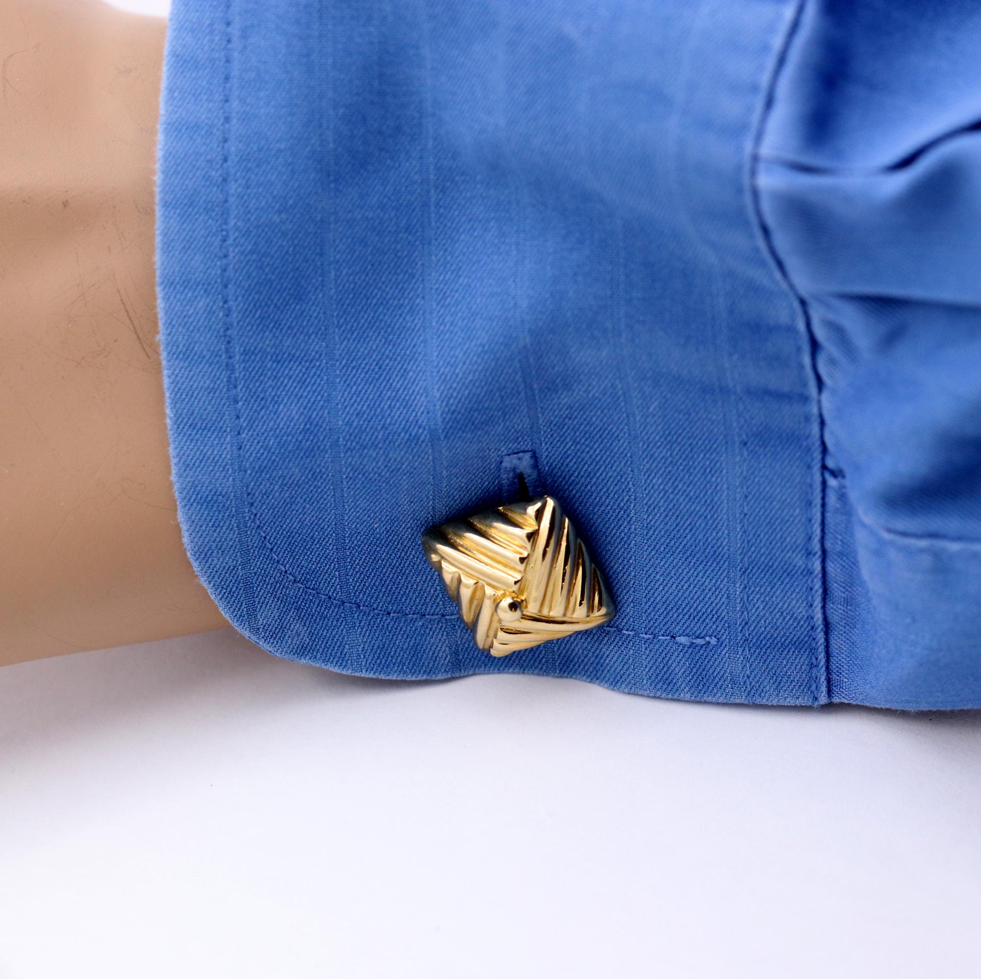 A pair of 18K yellow gold cuff links, measuring just over 1/2 an inch wide, and styled like square knots. With a ribbed design, they appear as though fabric was folded into this great design. Signed Emis, for Emis Beros of Palm Beach Florida, they