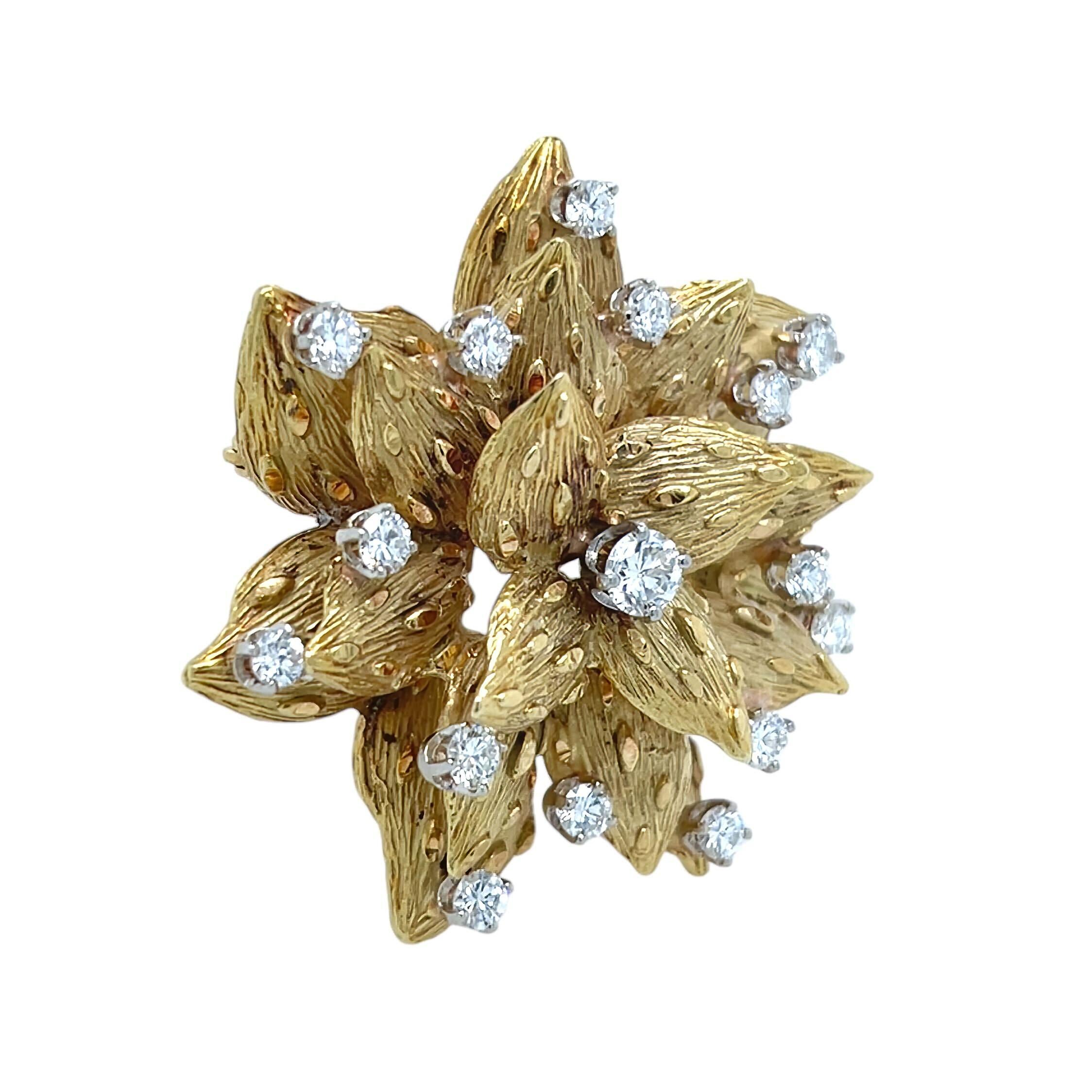 An 18 karat yellow gold and diamond brooch.  Designed as a many petaled highly textured flower centering a round brilliant cut diamond weighing approximately 0.33 carat and scattered with and additional 15 round brilliant cut diamonds.  Total