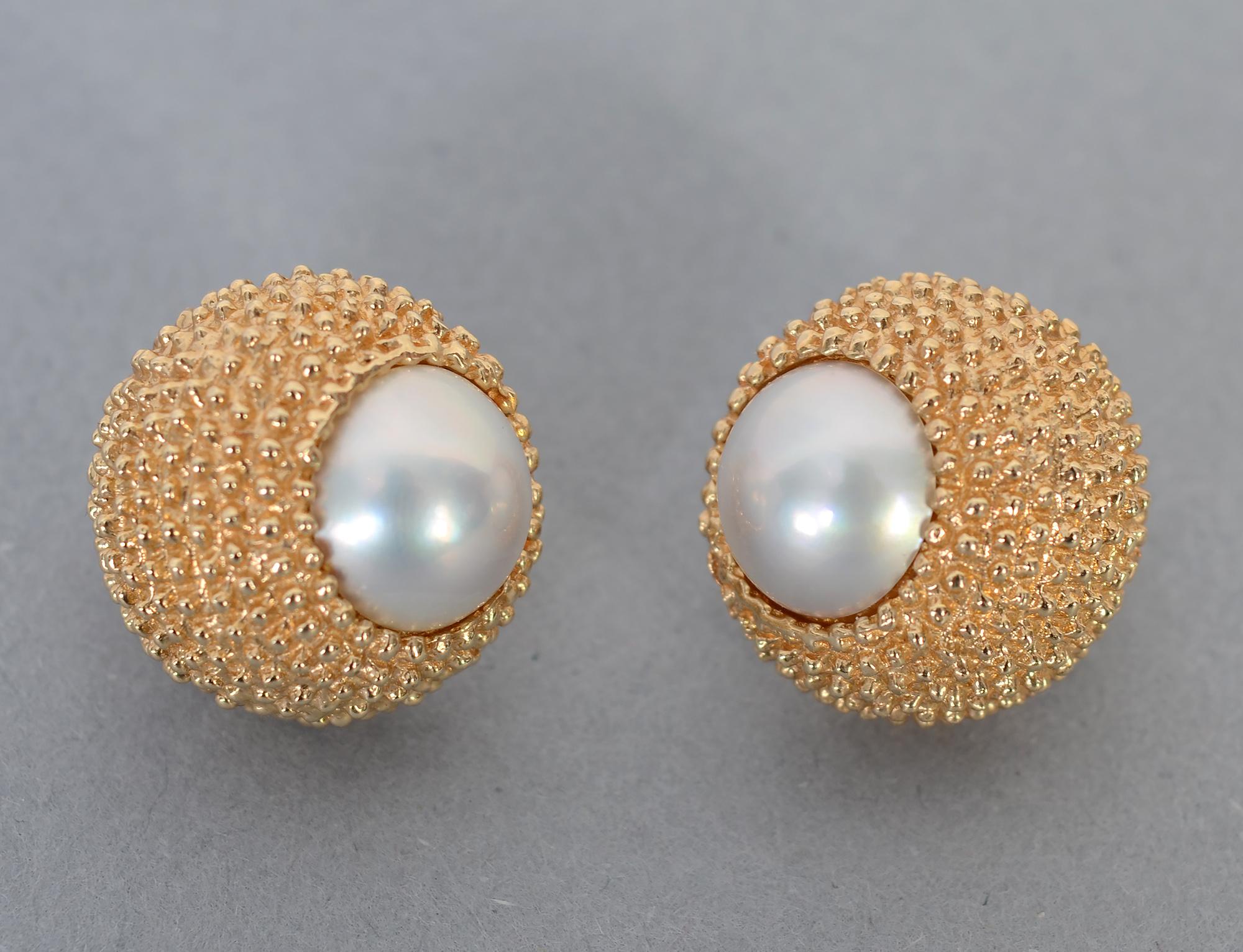 Attractive and unusual round gold earrings with a pearl set on the top end of each. The 14 karat gold is intricately textured with tiny beading.  The pearls are approximately 9 mm in width.
Backs are clips and posts. Posts can easily be removed to