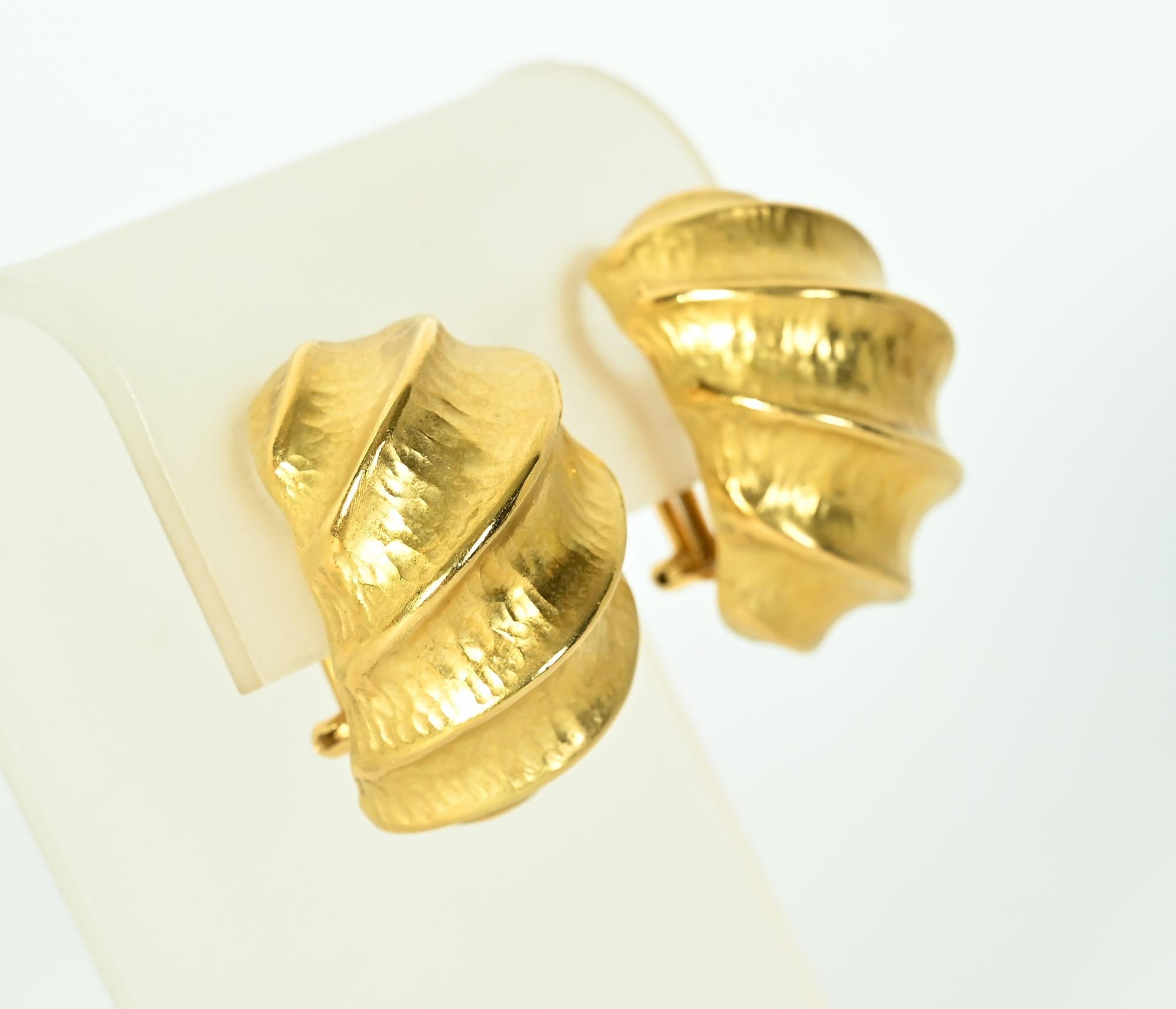 Ohrringe aus achtzehnkarätigem Gold mit gehämmerter Textur und erhabenem Wirbelmuster. Die Ohrringe sind kühn und ungewöhnlich in ihrer skulpturalen Musterung.
Rückseiten sind Pfosten und Klammern, die in Klammern umgewandelt werden können.