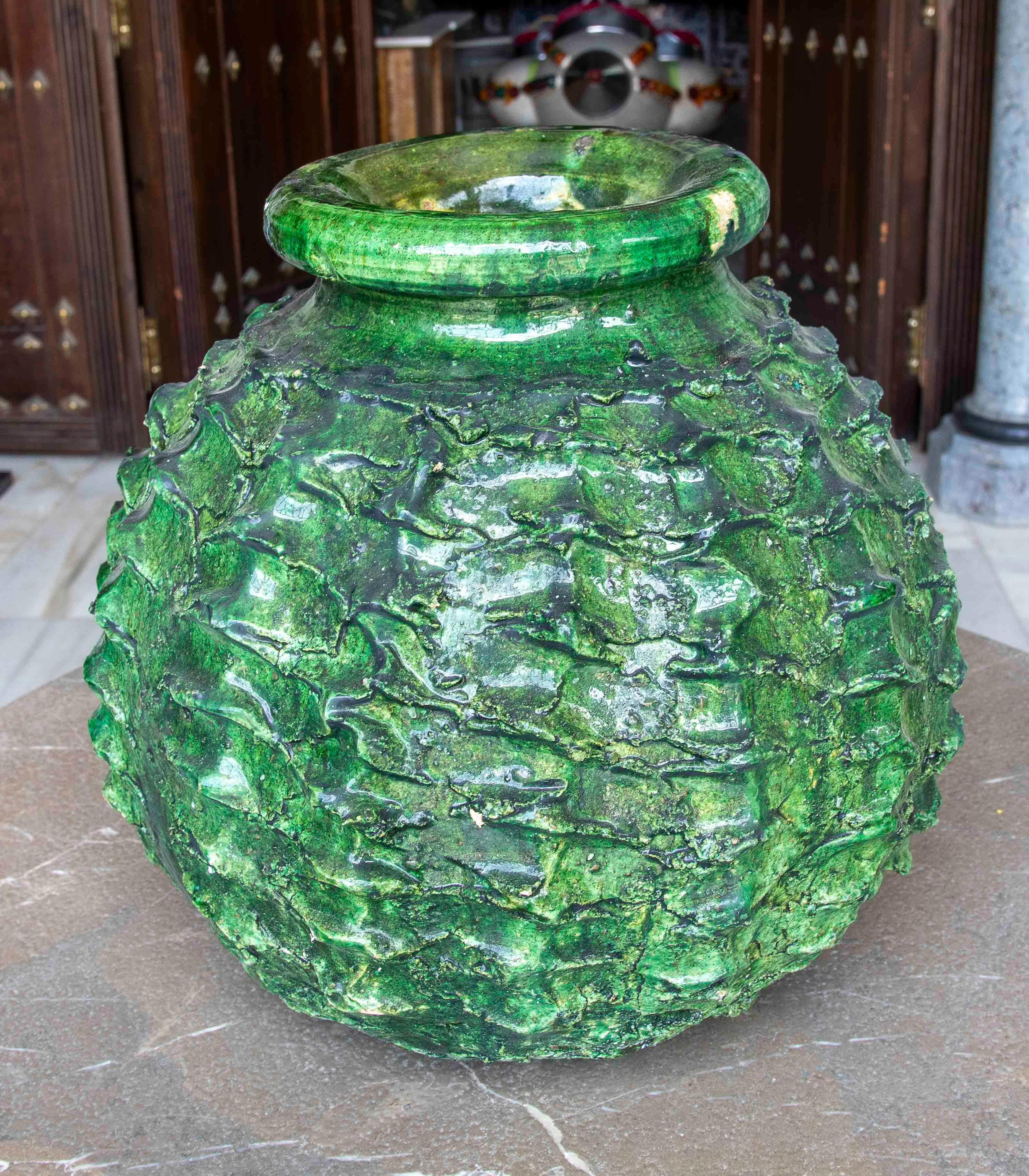 Stunning large ceramic vase with a glazed finish in intense green tones. Its surface features an organic texture reminiscent of tree bark or a pine cone, giving it a sculptural and naturalistic character. The glossy glaze accentuates its reliefs and