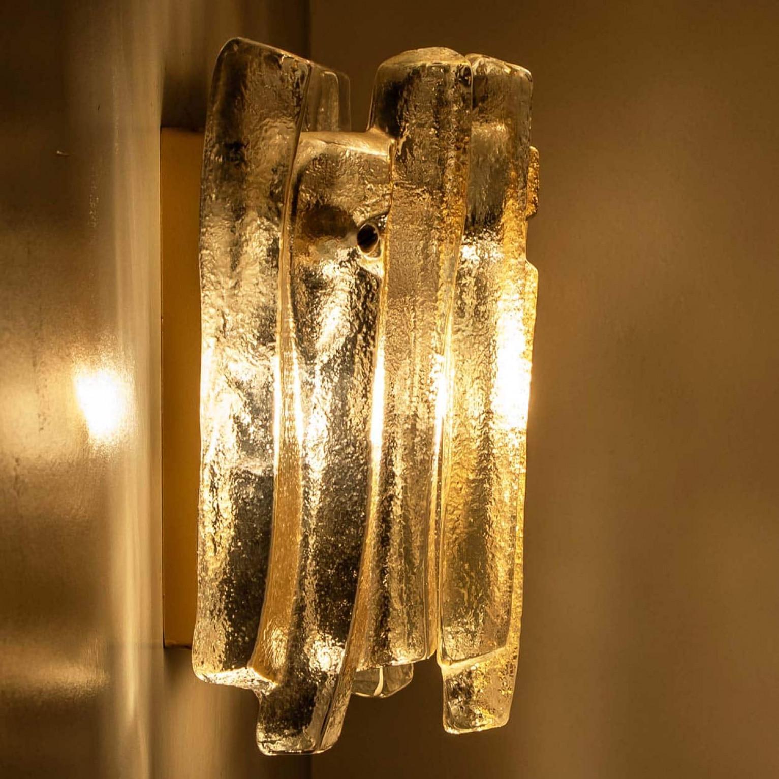 Beautiful and elegant modern wall lights in the style of Kalmar in the 1970s. A lovely design. Nine thick, textured glass beams in an organic, wave-like shape. The clear glass has an icy, handcrafted look, creating a sculptural and elegant effect.