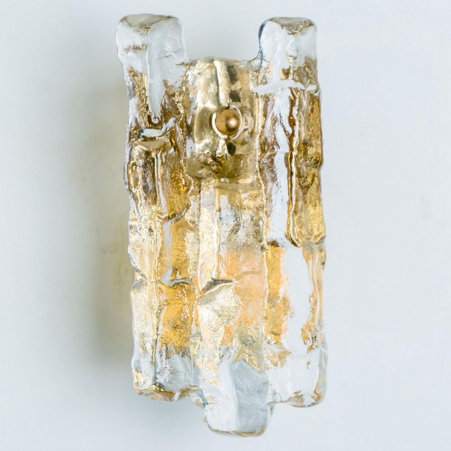 Beautiful high quality light fixture made by Kalmar, Austria. Manufactured in mid century, circa 1970 (at the end of 1960s and beginning of 1970s).

This wall light features lights made of handmade ice glass and brass back plate. The sides refract