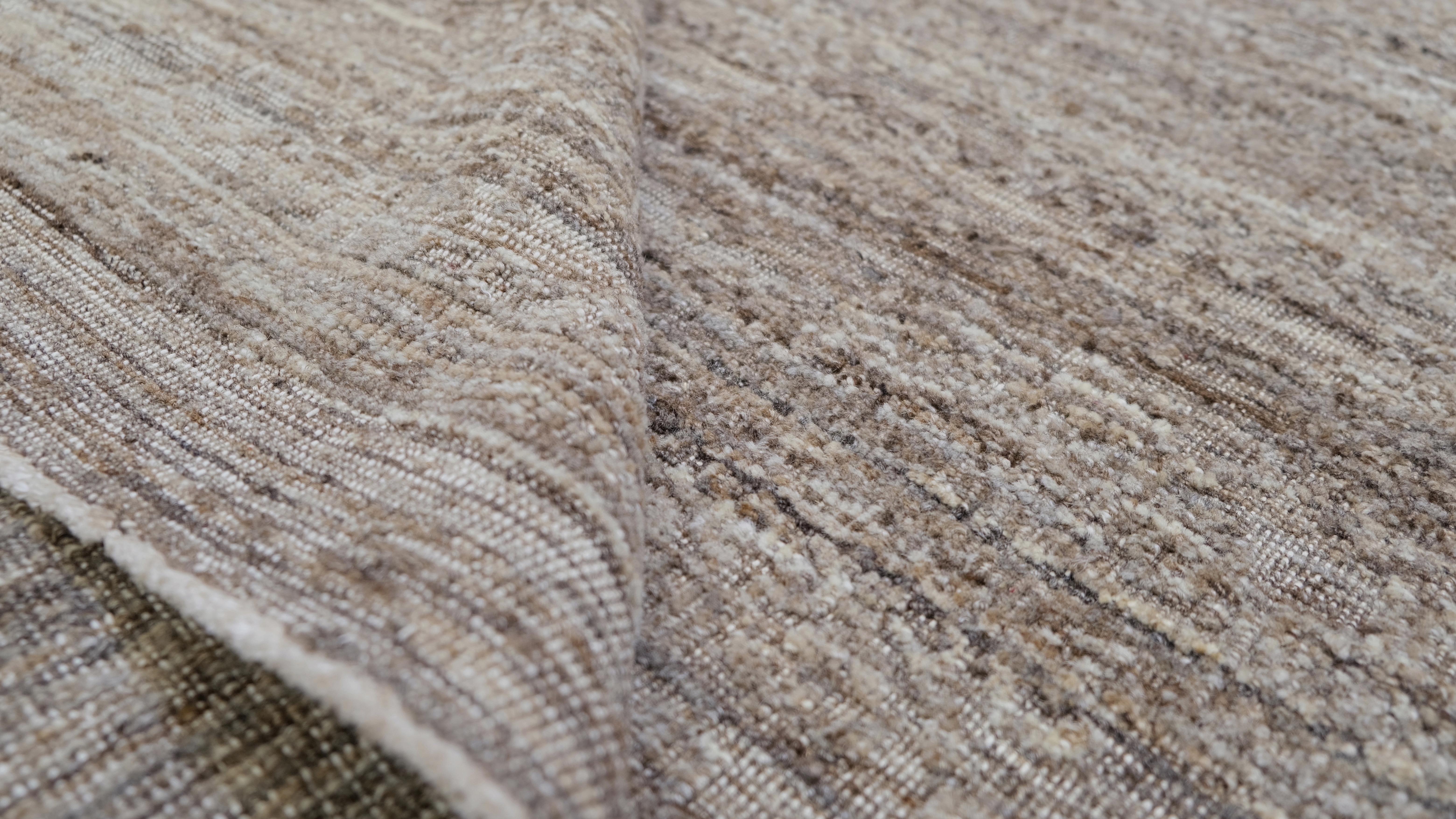 Introduce subtle elegance to your home with this exquisite hand-knotted wool rug. Featuring a natural, earthy color palette, the rug's textured design provides a sophisticated yet understated aesthetic that complements a variety of decor styles,
