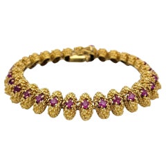 Gliederarmband aus strukturiertem Metall mit Rubinen im Rundschliff aus 18 Karat Gelbgold