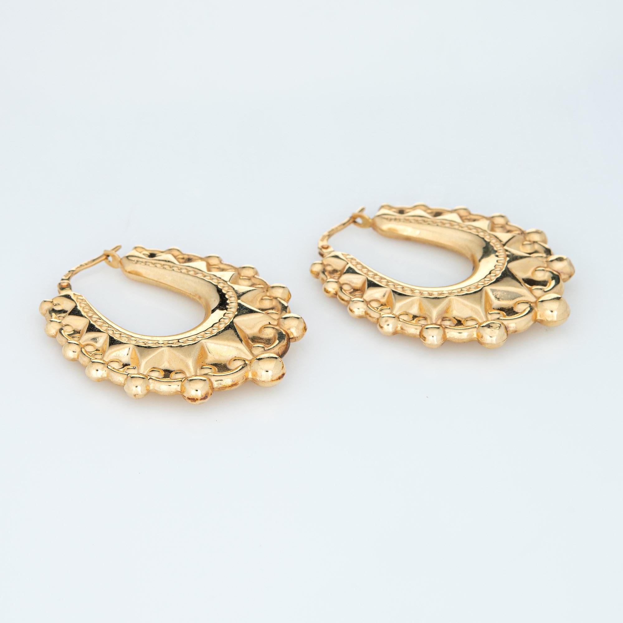 Fine detailed pair of oval hoop earrings crafted in 14k yellow gold. 

The stylish earrings feature an elaborate scrolled design with bead detailing. The hollow earrings offer a lightweight feel for a comfortable fit on the earlobe. The earrings are
