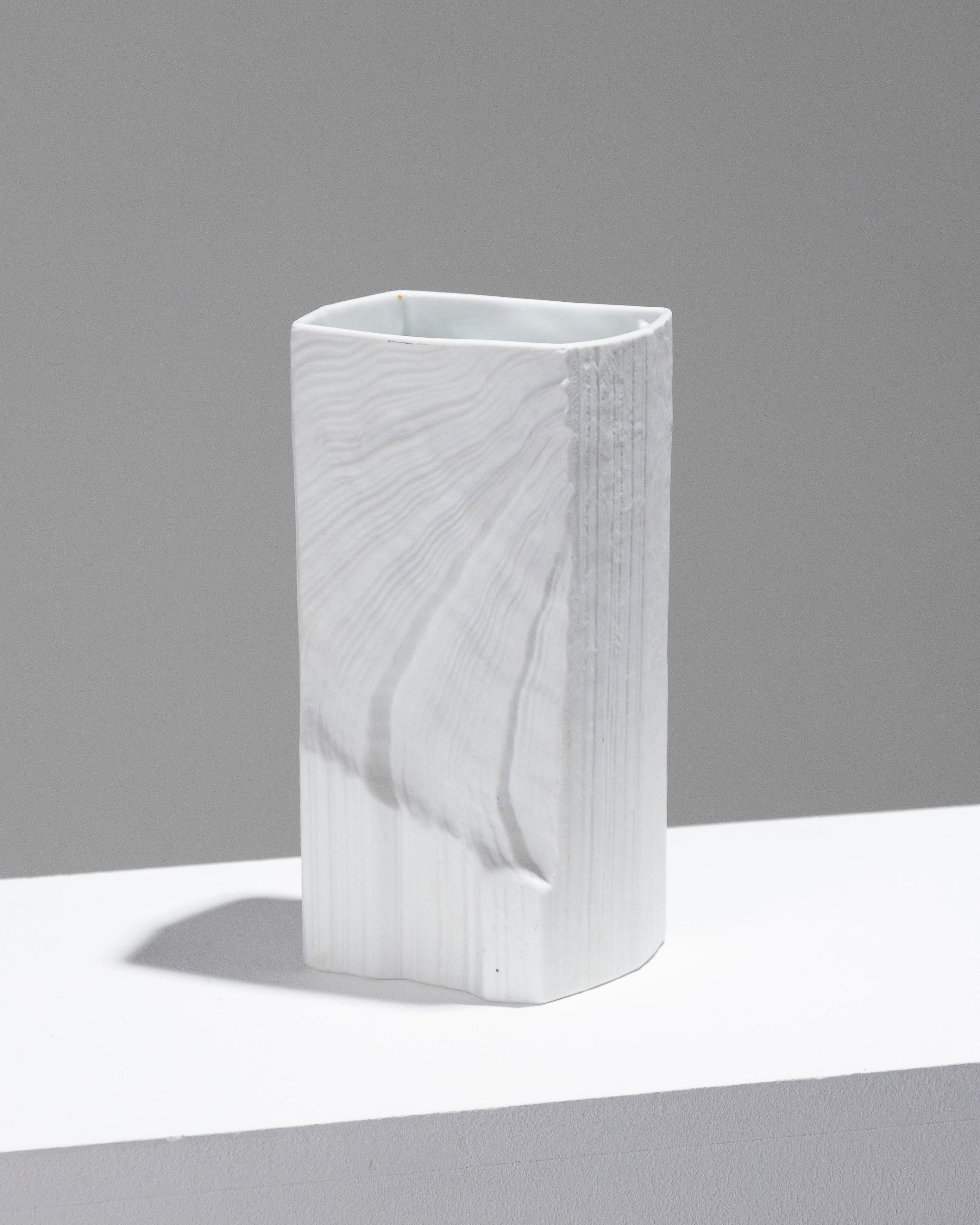 Vaso in porcellana strutturata, realizzato negli anni '80 dal produttore tedesco Rosenthal su disegno del pittore e ceramista Martin Freyer. Il pezzo presenta un corpo dritto su una base rettangolare, ornata da motivi a onda in rilievo. Timbro nero