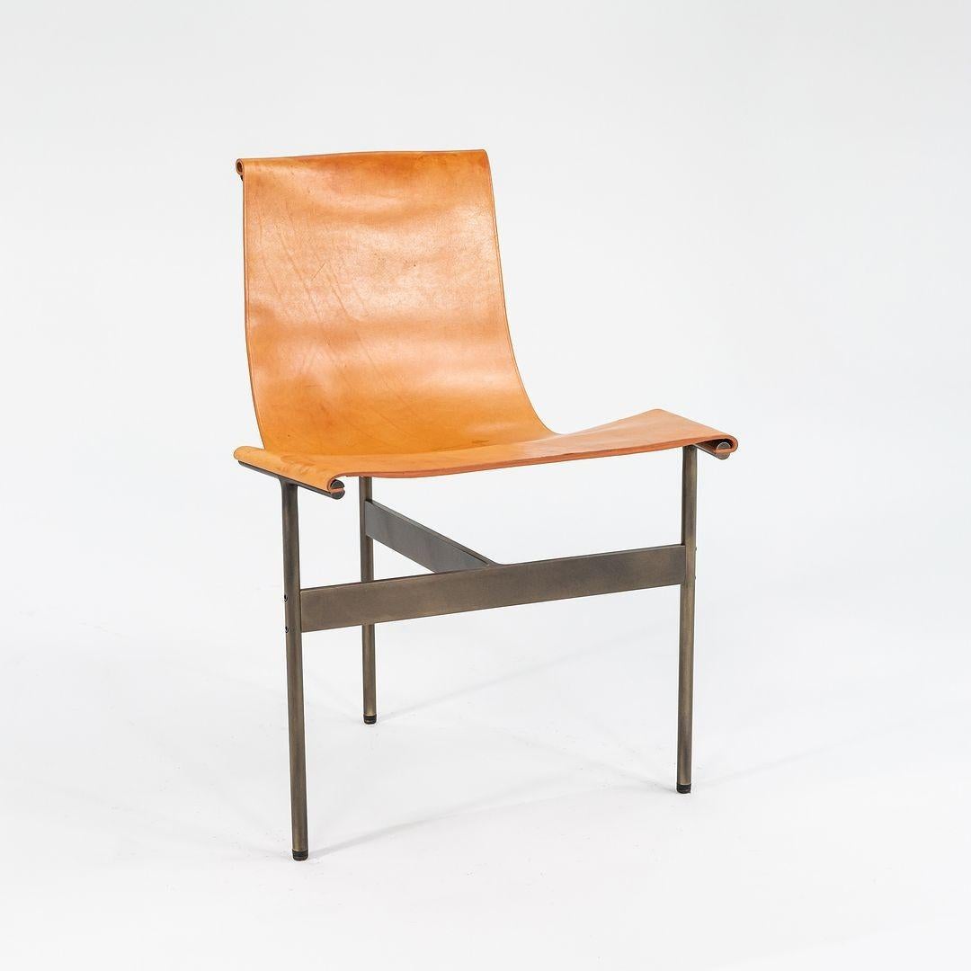 This is a TG-10 sling dining chair in tan leather with a medium antique bronze frame, produced by Gratz Industries. The chair was designed by Katavolos, Littell and Kelley in 1952 as part of the original Laverne Collection produced by Gratz