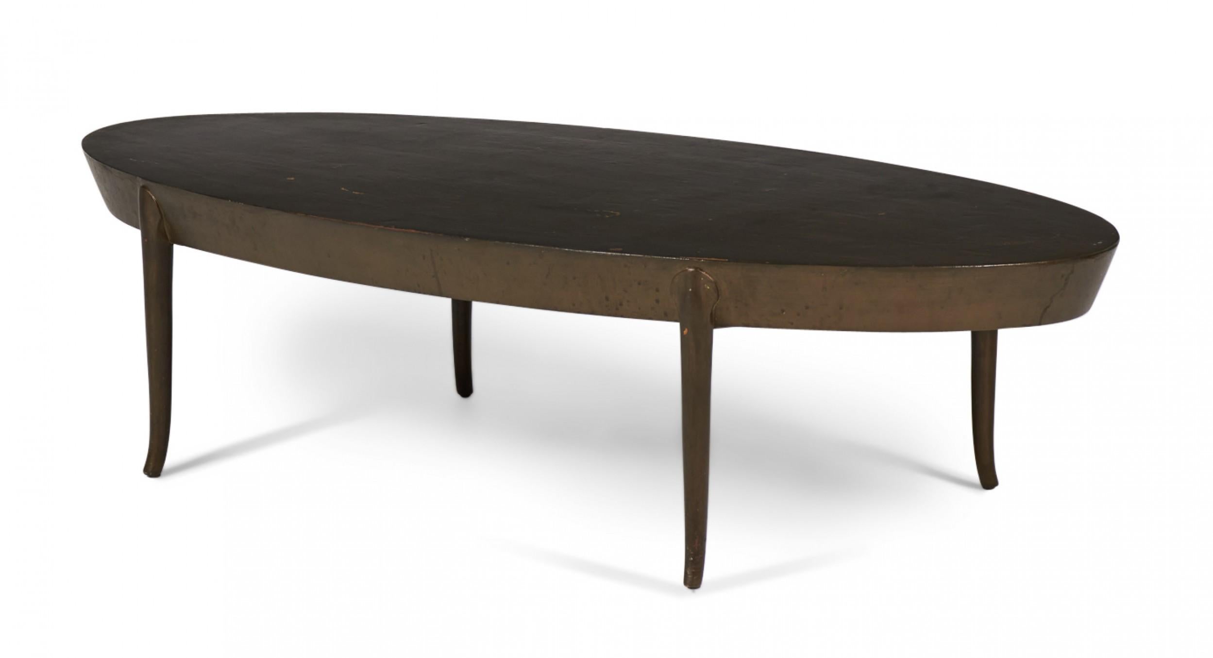 American Mid-Century oval wooden cocktail / coffee table with a thick tapered top resting on four round legs with gently curved feet. (T.H. ROBSJOHN-GIBBINGS)
