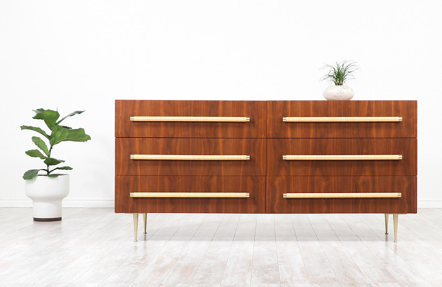 Stylish modern dresser designed by British-born architect T.H. Robsjohn-Gibbings for Widdicomb in the United States, circa 1950s. This striking design features a sturdy walnut wood case with six drawers and solid brass legs perfectly complementing