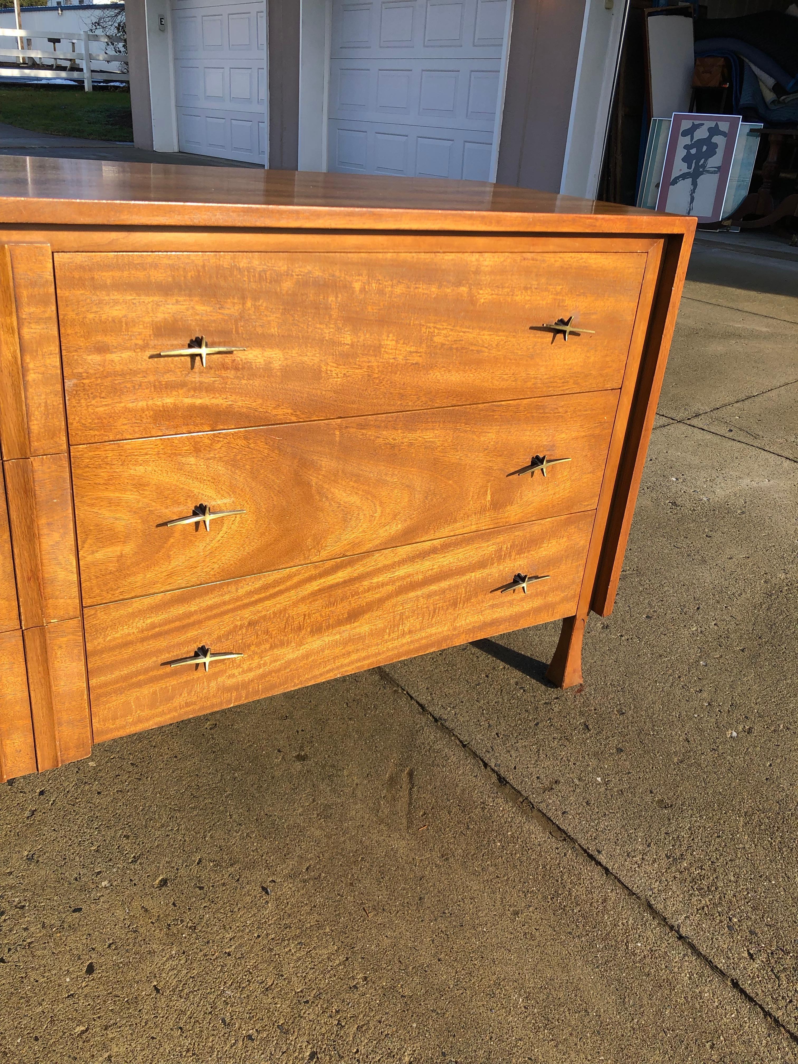 This exquisite dresser is made out of wood, solid wood, and veneer, and is in good condition. This dresser is a delightful example of the Mid-Century Modern style; it has a Classic Silhouette, charming handles, and a luscious medium walnut finish