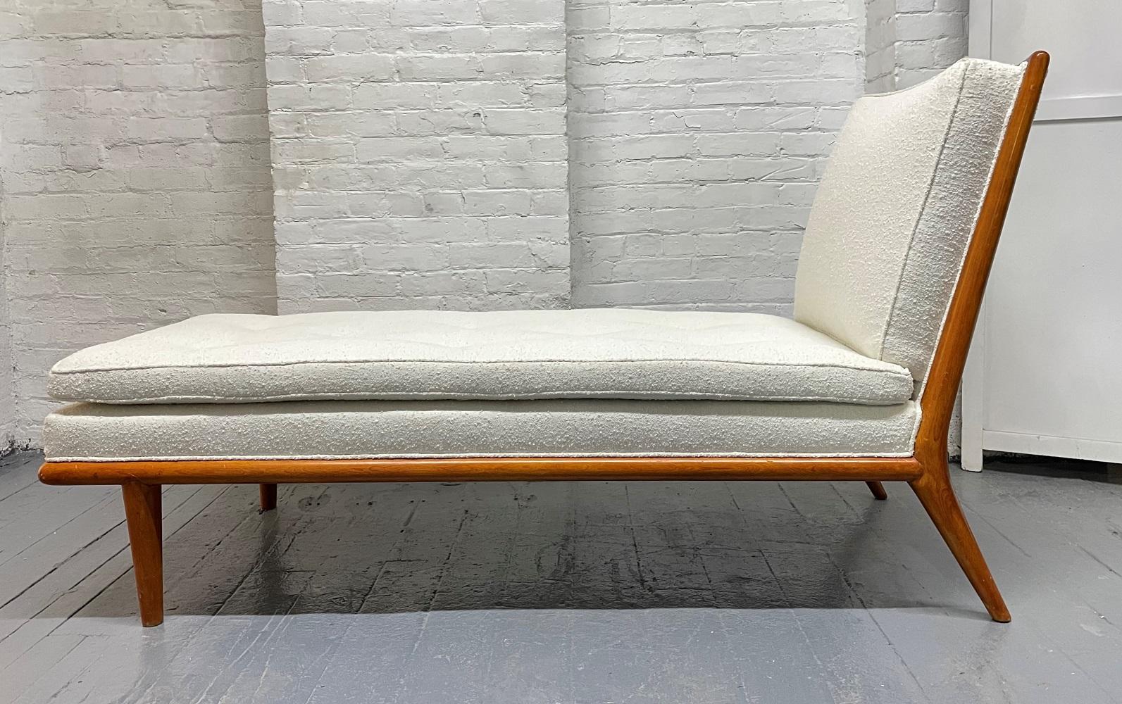 T.H. Robsjohn-Gibbings chaise lounge for Widdicomb. Upholstered in Bouclé with a walnut frame. The chaise lounge has a tufted seat and splayed rear legs.