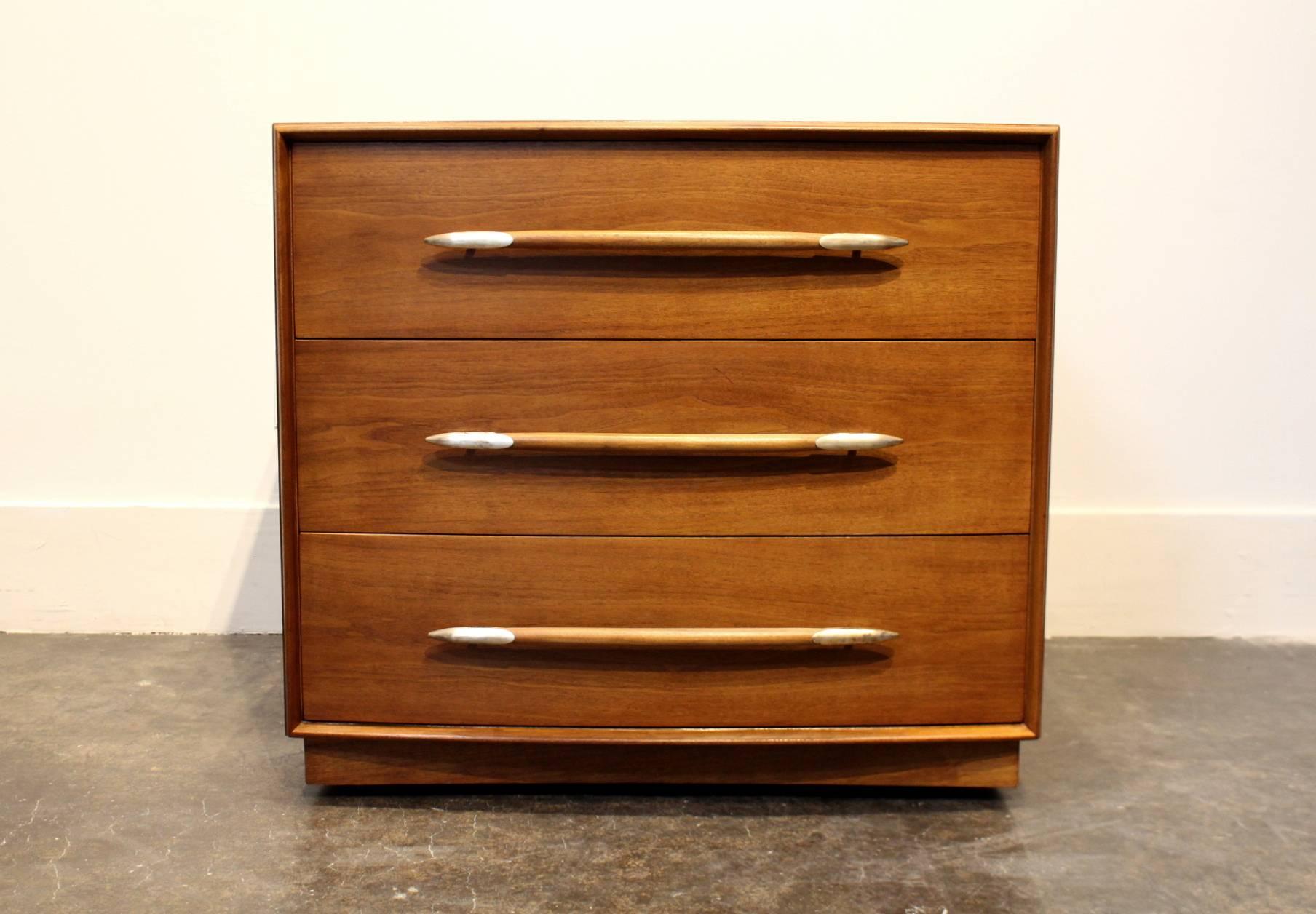 Chest of drawers for Widdicomb, from British architect, interior decorator, and furniture designer; Robsjohn-Gibbings, circa 1950s. Three large drawers with long horizontal pulls capped with brass darts. The whole raised on a plinth base on caster