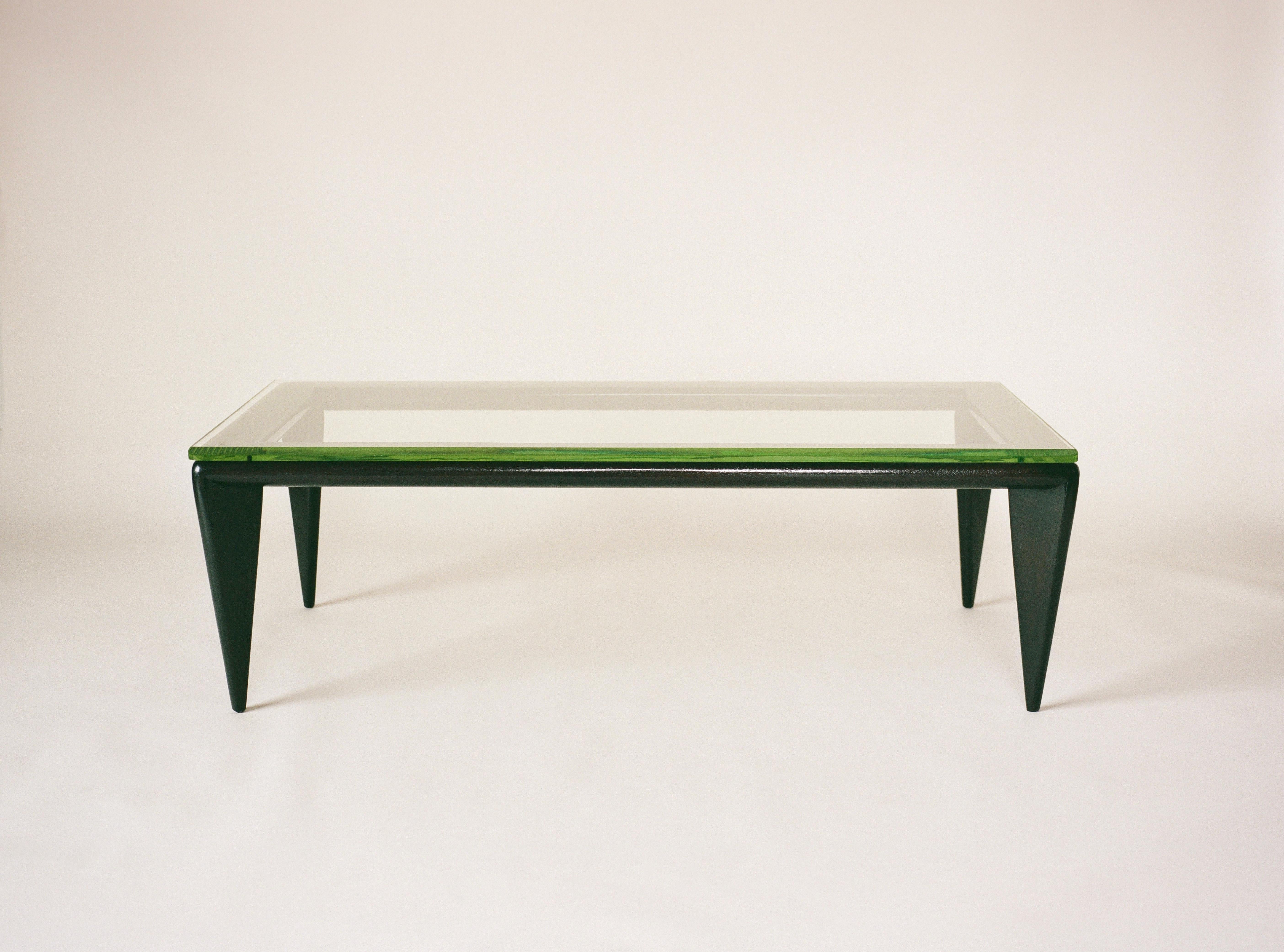 “A custom group designed by T.H. Robsjohn-Gibbings for Widdicomb Furniture Co., Grand Rapids” reads the original print ad that ran in 1948 featuring this table. A dark stained oak wood base supports a thick cut, bevelled glass top with an emerald