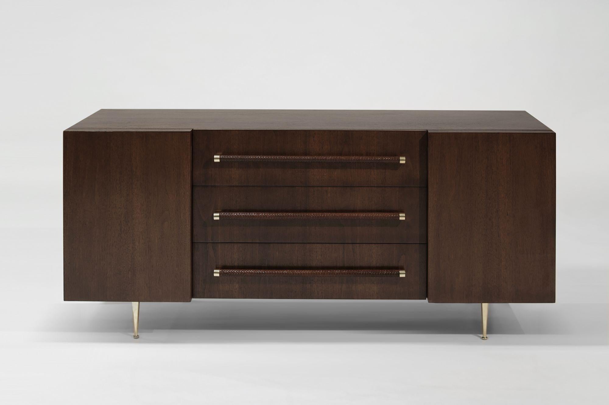 Creato da T.H. Robsjohn-Gibbings per Widdicomb, 1950-1959 circa, questa cassettiera d'epoca in noce mette in mostra la raffinata maestria del Mid-Century. Presenta ante laterali che rivelano scaffali, tre cassetti centrali ornati da fettucce di