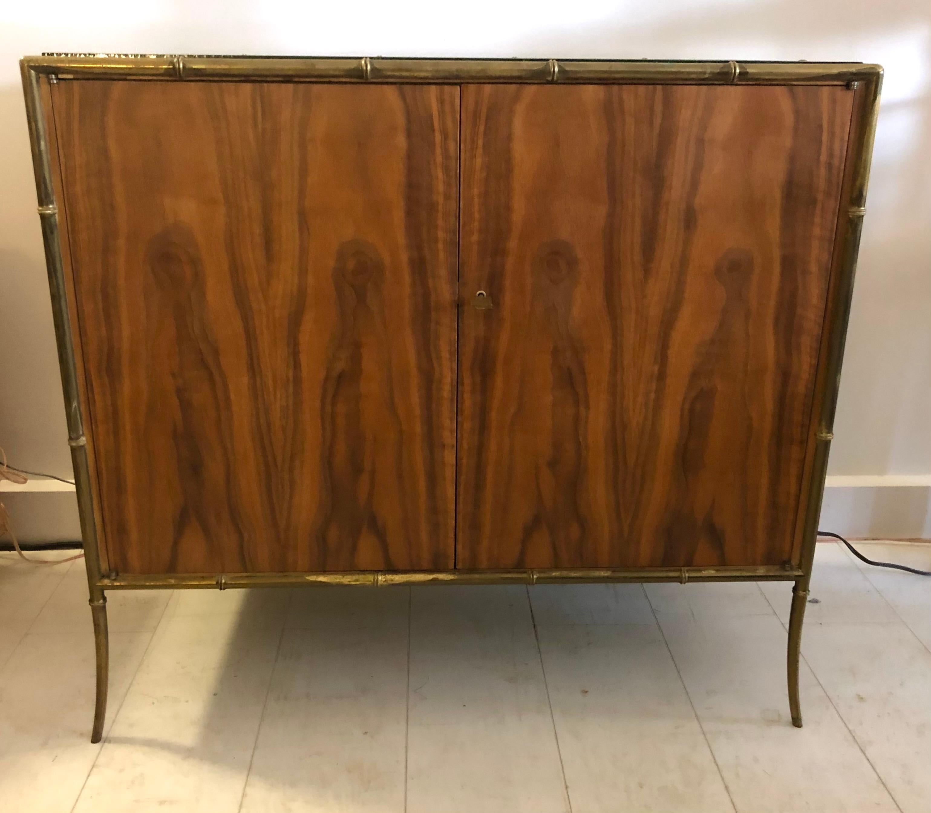 One-of-a-kind two-door cabinet in exotic hardwood with solid cast brass bamboo frame, and black glass work-surface top, designed as a living room bar for the Kandell Penthouse apartment at the original Ritz Carlton on Park Ave. South. 

This 1953