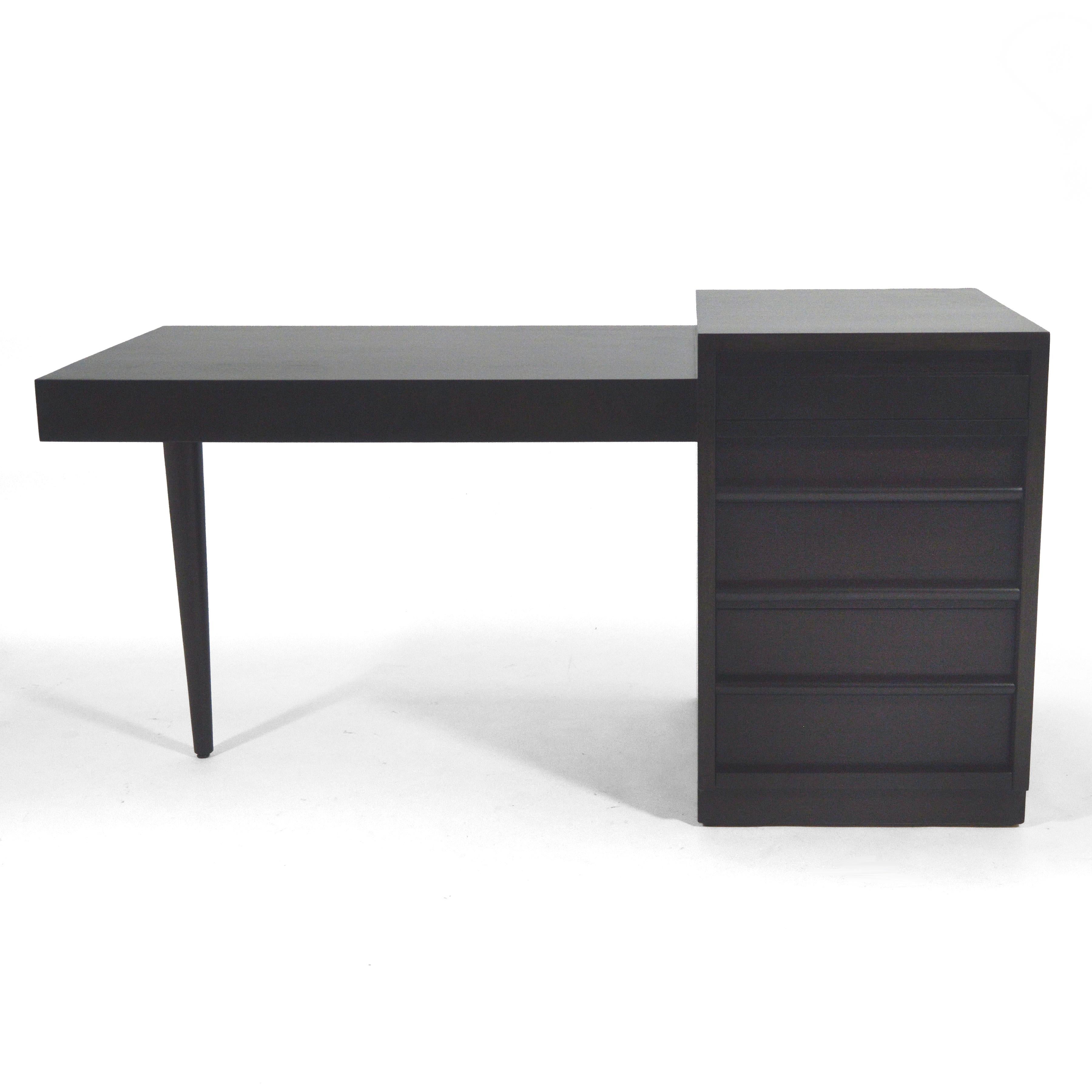 This desk by T.H. Robsjo-Gibbings for Widdicomb has a strong architectural quality and great minimalist design. The desktop cantilevers from the pedestal and is supported by a single conical leg.

Pedestal features a pencil drawer, a pull-out