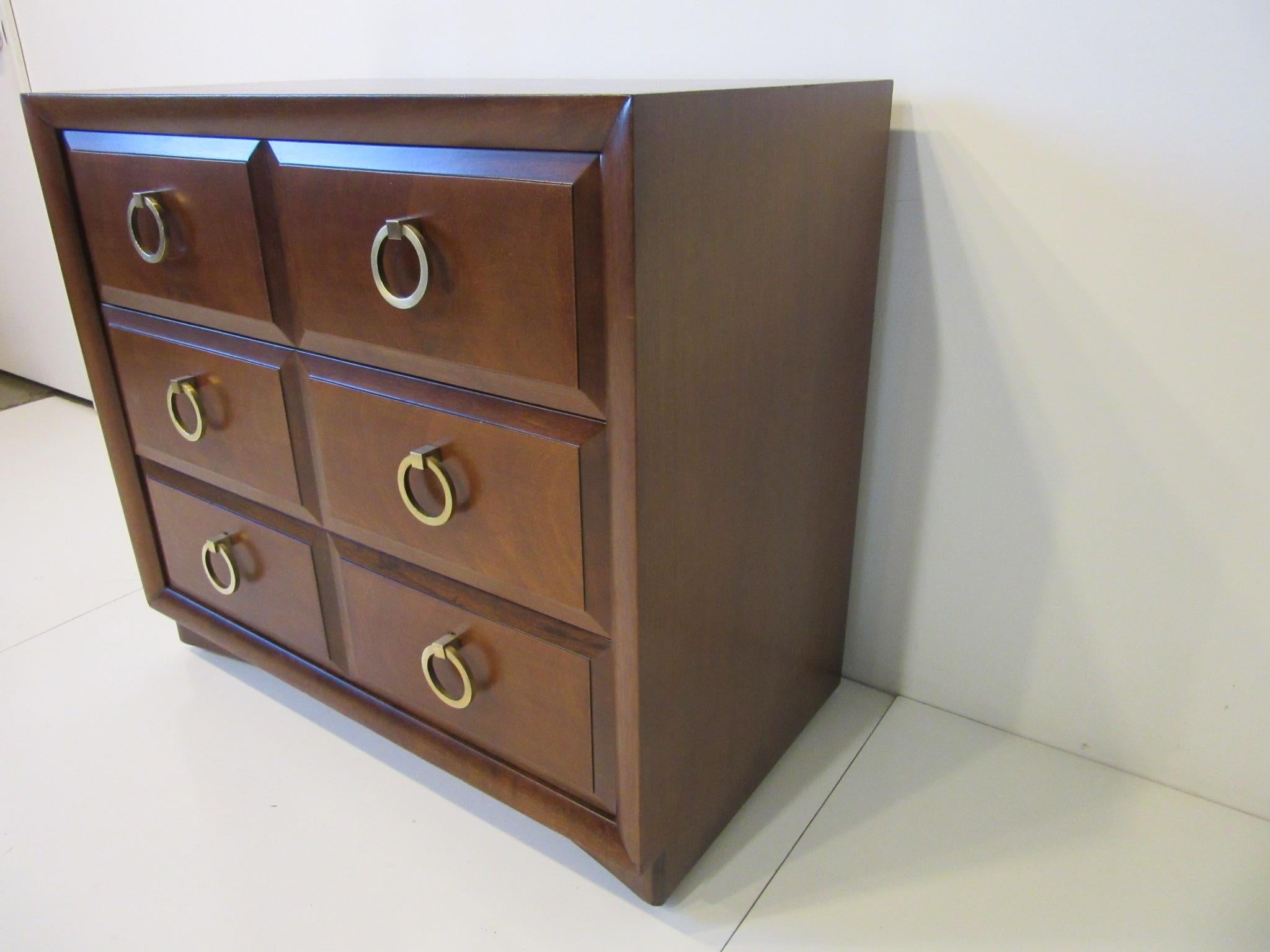 A well crafted three drawer medium dark mahogany dresser / chest with heavy brass ring pulls sitting on a curved kick base. Retains the original manufactures tag by the Widdicomb Furniture company Grand Rapids Michigan, a nice smaller sized chest