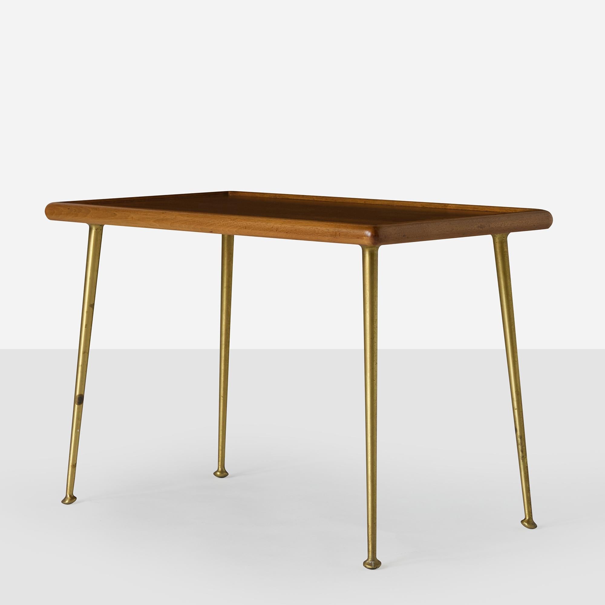 A wooden end table sitting atop four slightly sabred legs in spun brass. Widdicomb decal label and stenciled numbers. Legs are in original condition. Table top has been refinished and stained a warm walnut tone.