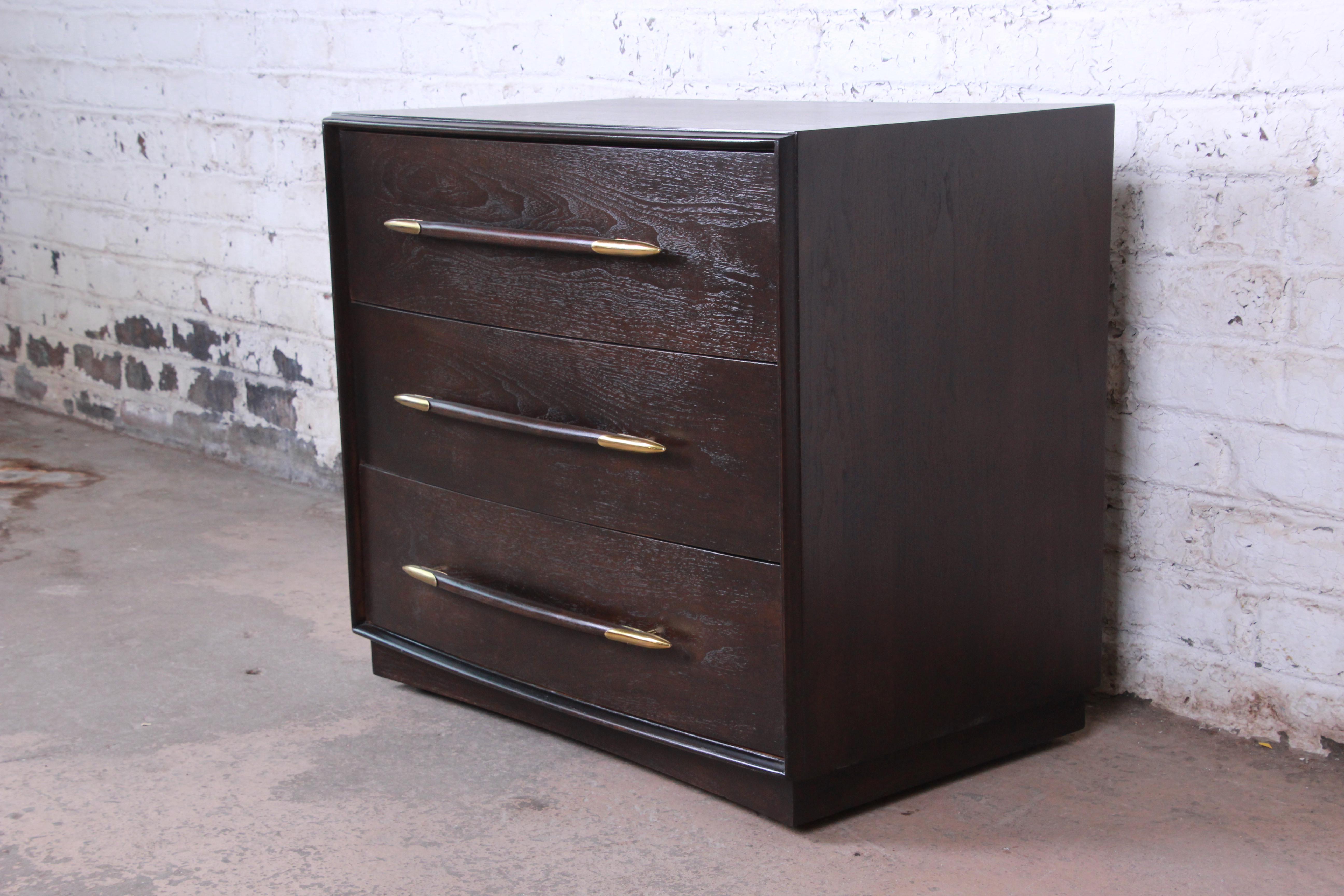 Offering an outstanding Mid-Century Modern three-drawer bachelor chest or large nightstand designed by T.H. Robsjohn-Gibbings for Widdicomb. The chest features gorgeous walnut wood grain and unique original spear-shaped drawer pulls. The walnut case