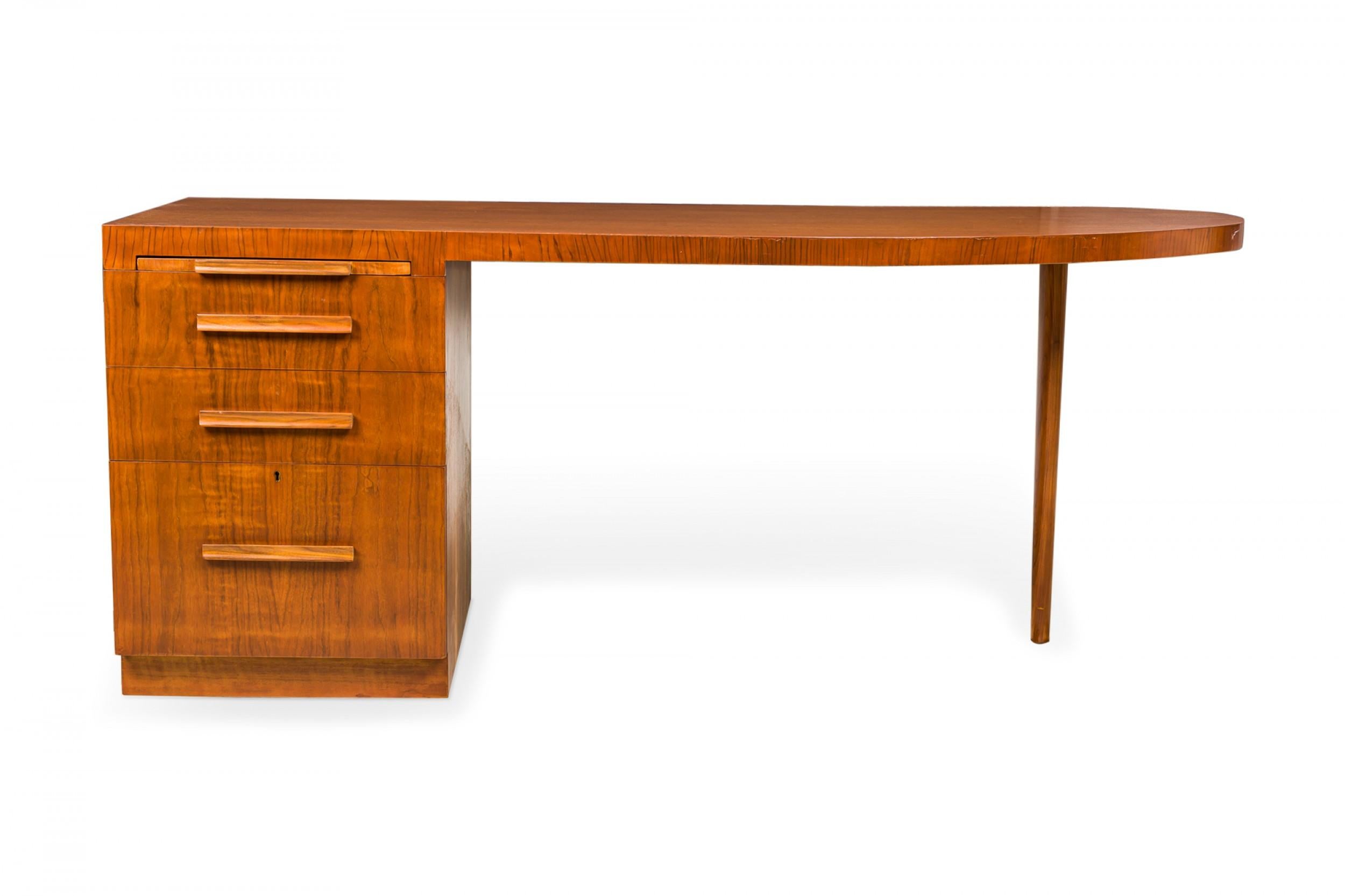 American mid-century walnut desk with a top squared on the left over a set of four drawers in graduated heights with wooden bar drawer pulls, and rounded on the right, supported by a tapered dowel leg. (T.H. ROBSJOHN-GIBBINGS FOR WIDDICOMB FURNITURE