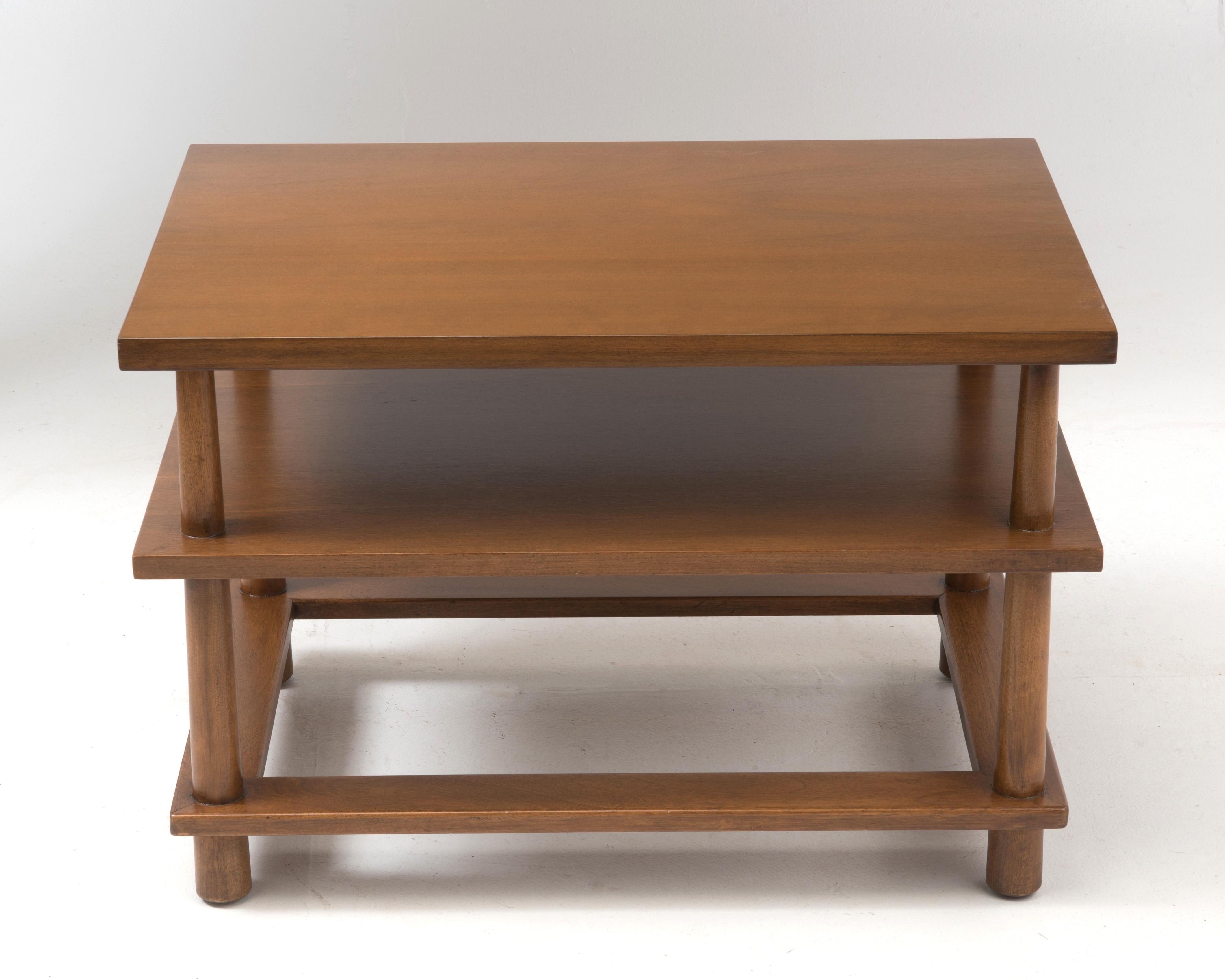A restored T.H. Robsjohn-Gibbings designed side table manufactured by Widdicomb in 1957. The tables feature beechwood reverse tapered legs and a walnut tabletop, middle shelf and bottom frame.