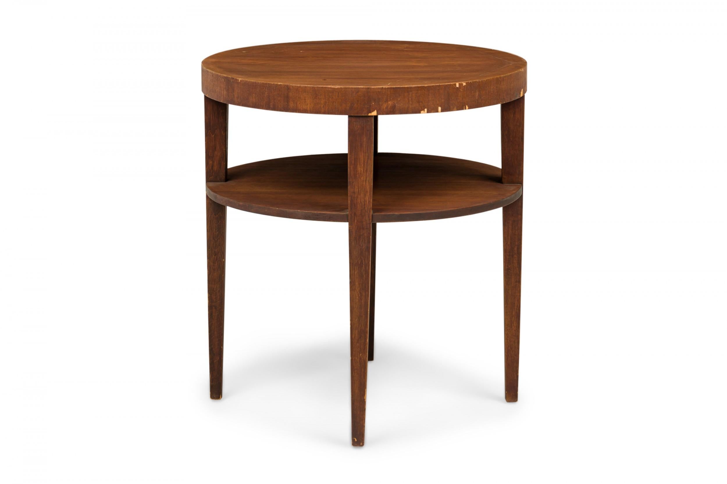 Mid-Century circular two-tier end / side table with a circular top and lower shelf, supported by four tapered square legs, finished in walnut veneer. (T.H. ROBSJOHN-GIBBINGS)
