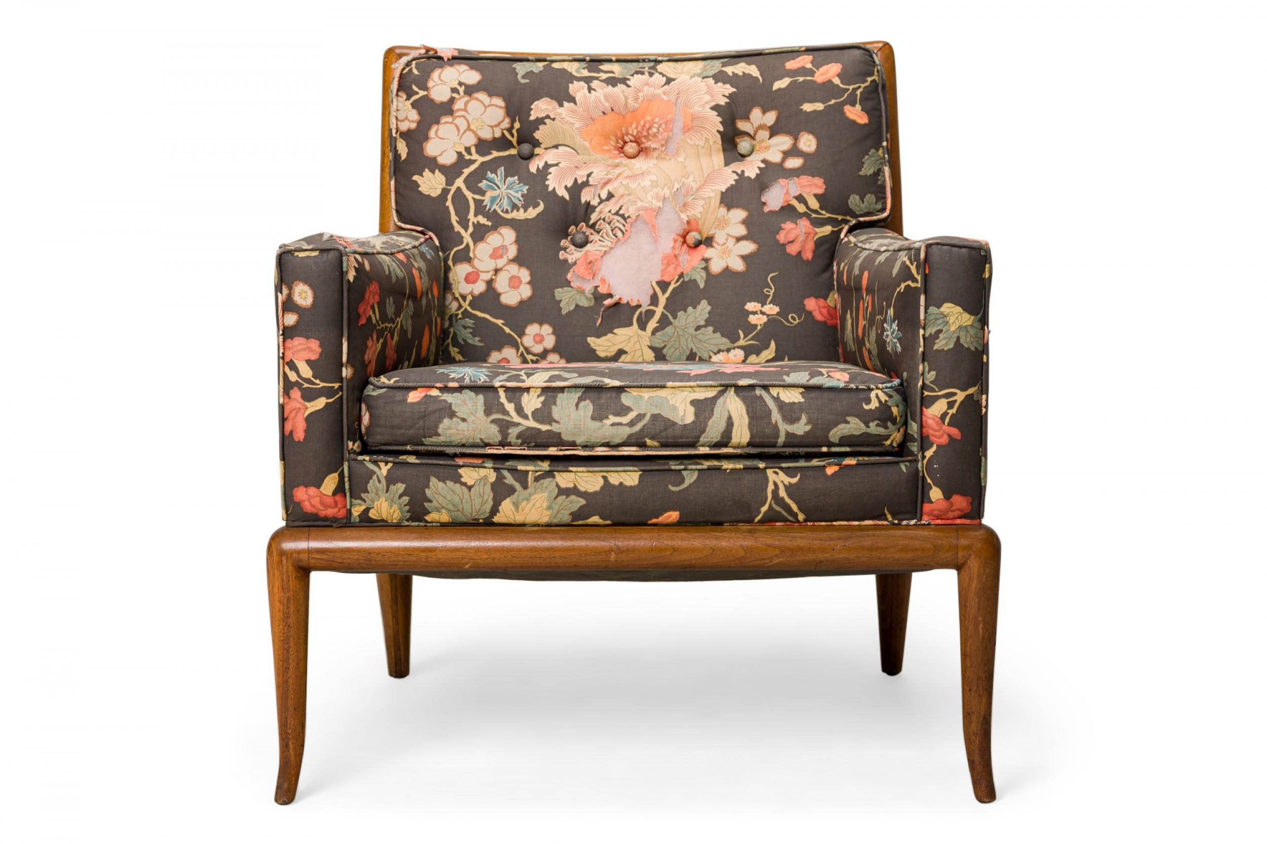American mid-century lounge / armchair with a square walnut frame, upholstered in a fabric with a bright floral pattern against a black background with a button-tufted back, resting on four slightly curved and tapered walnut legs.(T.H.