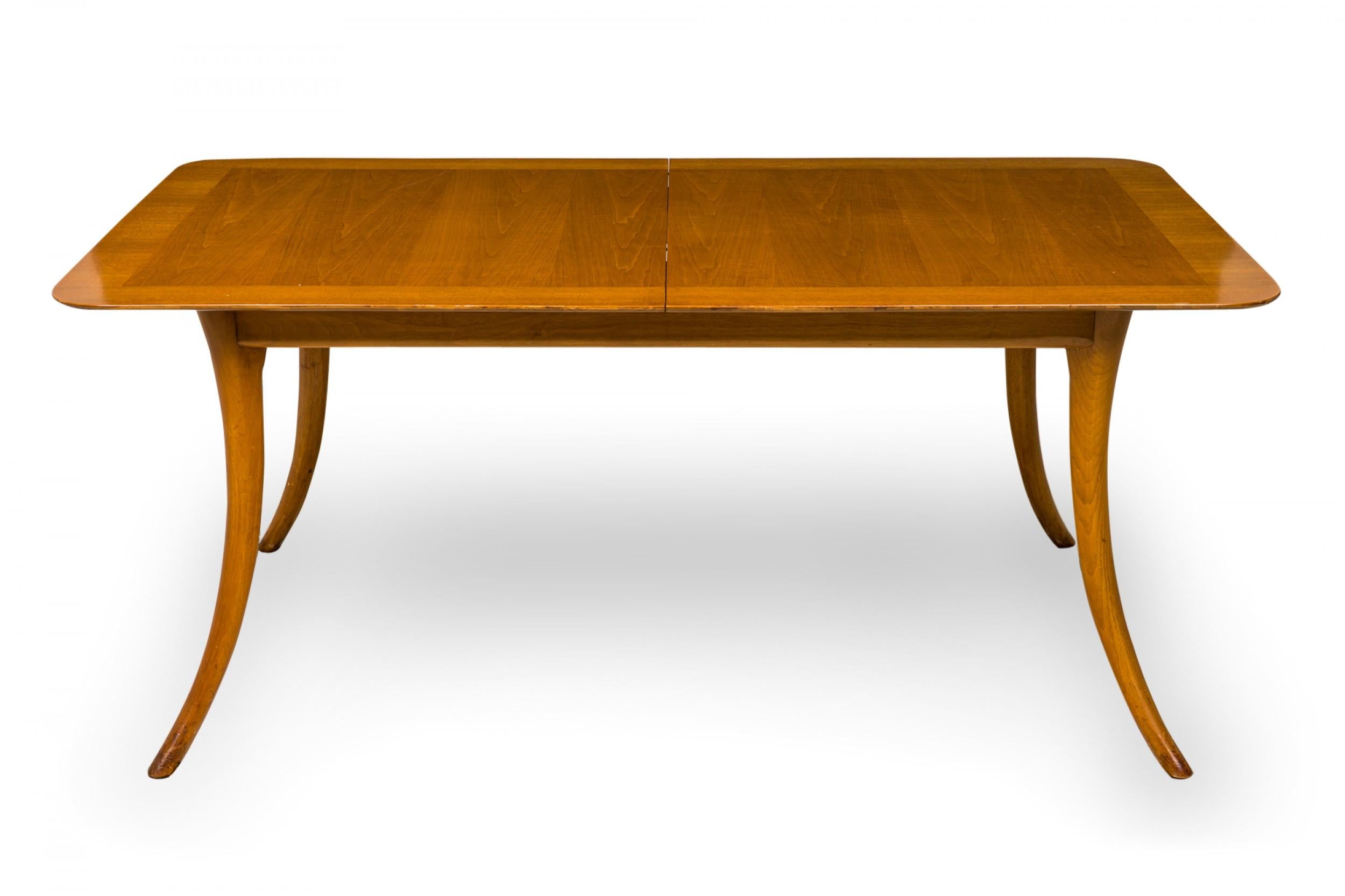 Table de salle à manger / conférence rectangulaire en noyer du milieu du siècle, aux angles arrondis, avec deux allonges, reposant sur quatre pieds sabre. (AT&T. ROBSJOHN-GIBBINGS POUR WIDDICOMB FURNITURE COMPANY)

La largeur totale avec les