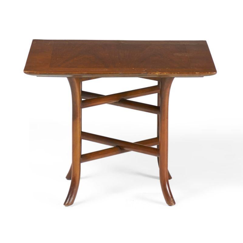 American Mid-Century (1950s) walnut occasional / side table with a square top supported by a crossed trestle base with curved sabre feet. (T.H. ROBSJOHN-GIBBINGS FOR WIDDICOMB FURNITURE)(Similar pieces with different finishes: DUF0147A-C)
