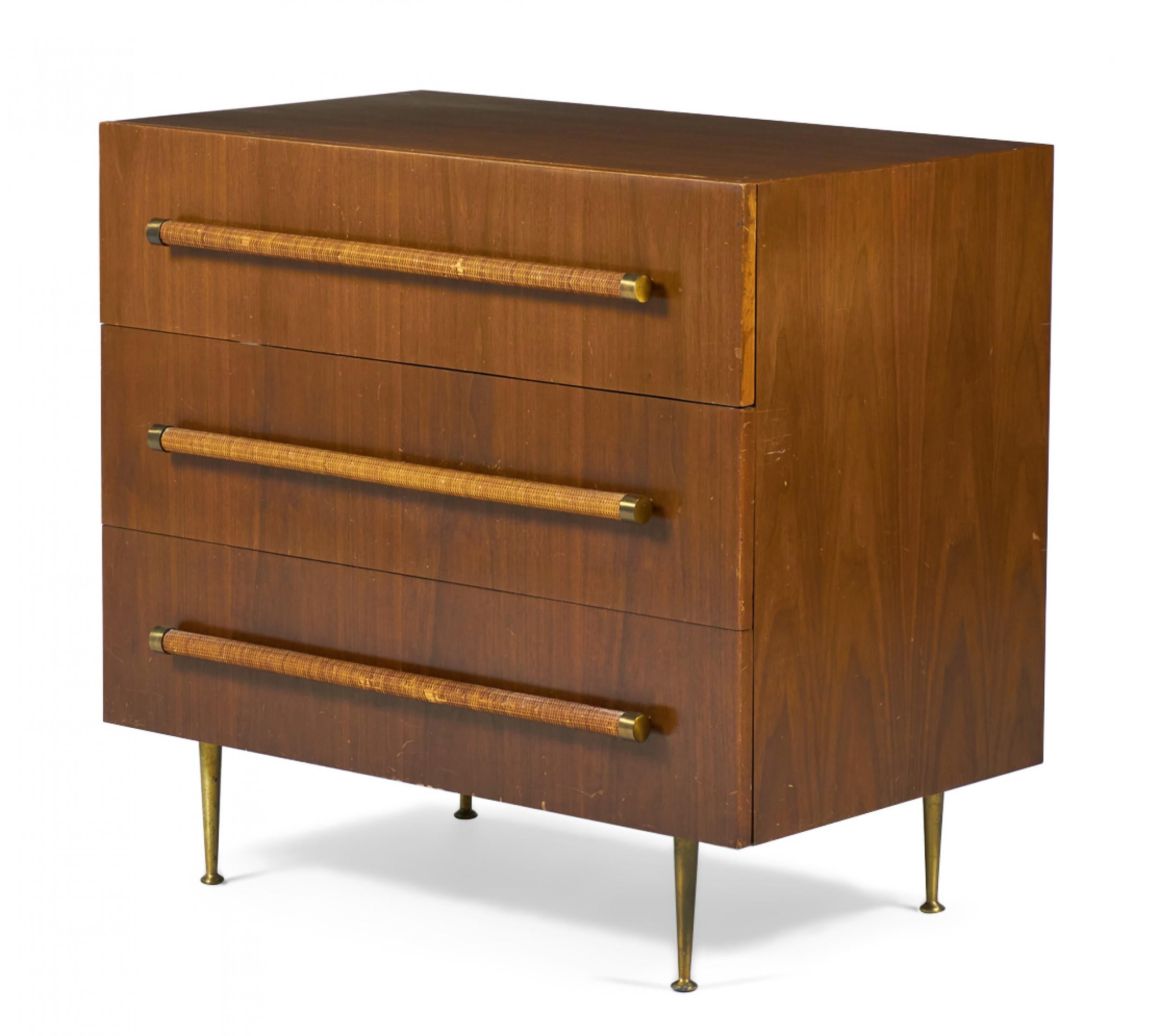 American Mid-Century (1950s) walnut three-drawer chest of drawers with rattan-wrapped dowel drawer pulls and four tapered brass legs with circular brass feet. (T.H. Robsjohn-Gibbings for Widdicomb).
    
